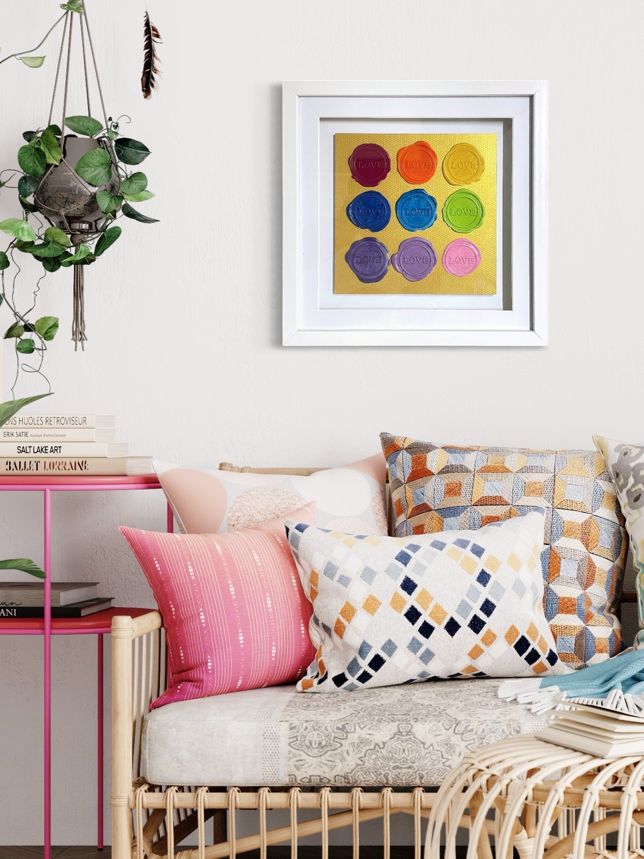 Cozy sofa, patterned cushions, pink side table, books, plant, and Kate Mayer’s Sealed Intention - Love is Love wall art.