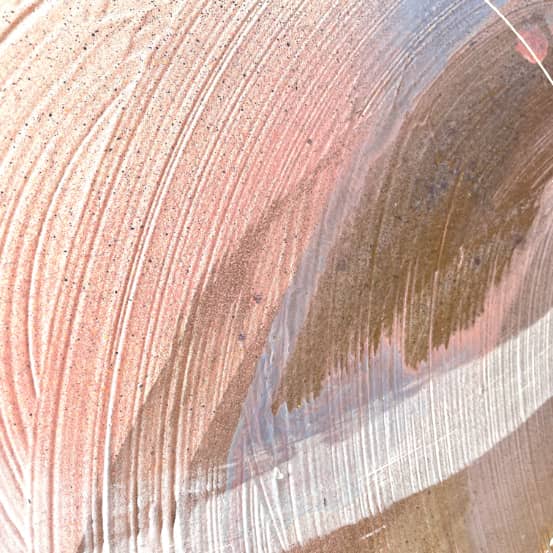 Close-up of the "Just Be" painting by Kate Mayer, highlighting an abstract composition with textured pink, brown, and white brushstrokes featuring curved and layered patterns created using acrylic and spray paint.