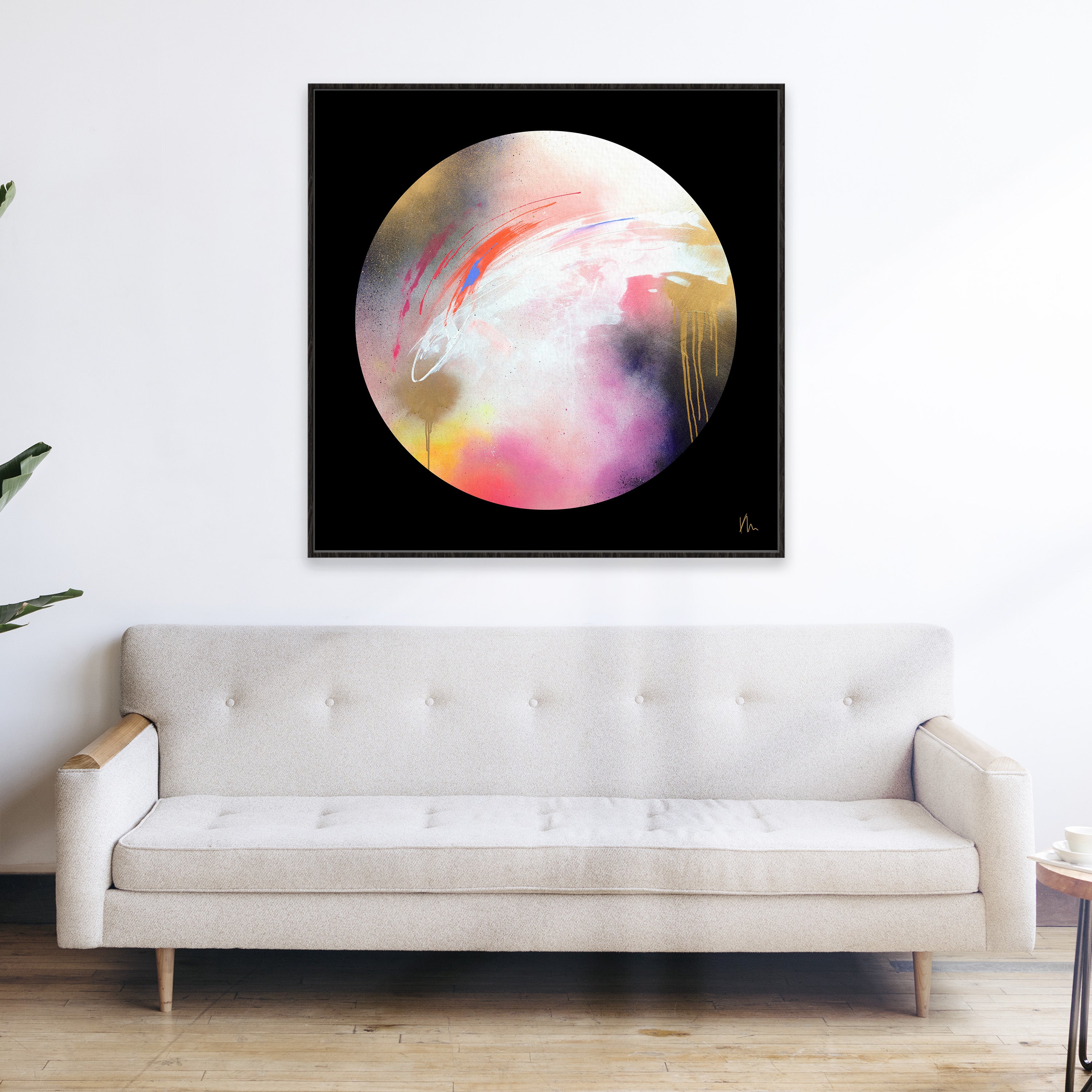 A modern living room featuring The Dream Starts Here, a colorful abstract painting with a circular design by Kate Mayer, hanging above a beige tufted sofa to create a vibrant focal point in your home decor.
