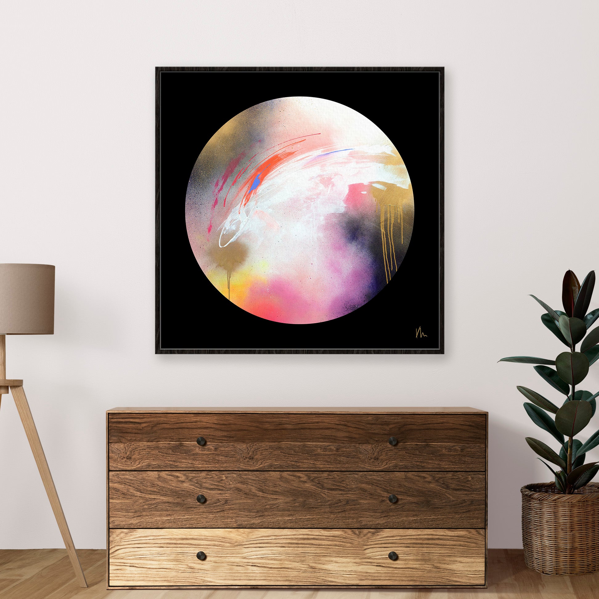 A modern room featuring "The Dream Starts Here" wood dresser by Kate Mayer, complemented by abstract circular artwork, a stylish lamp, and a potted plant against a pristine white wall.