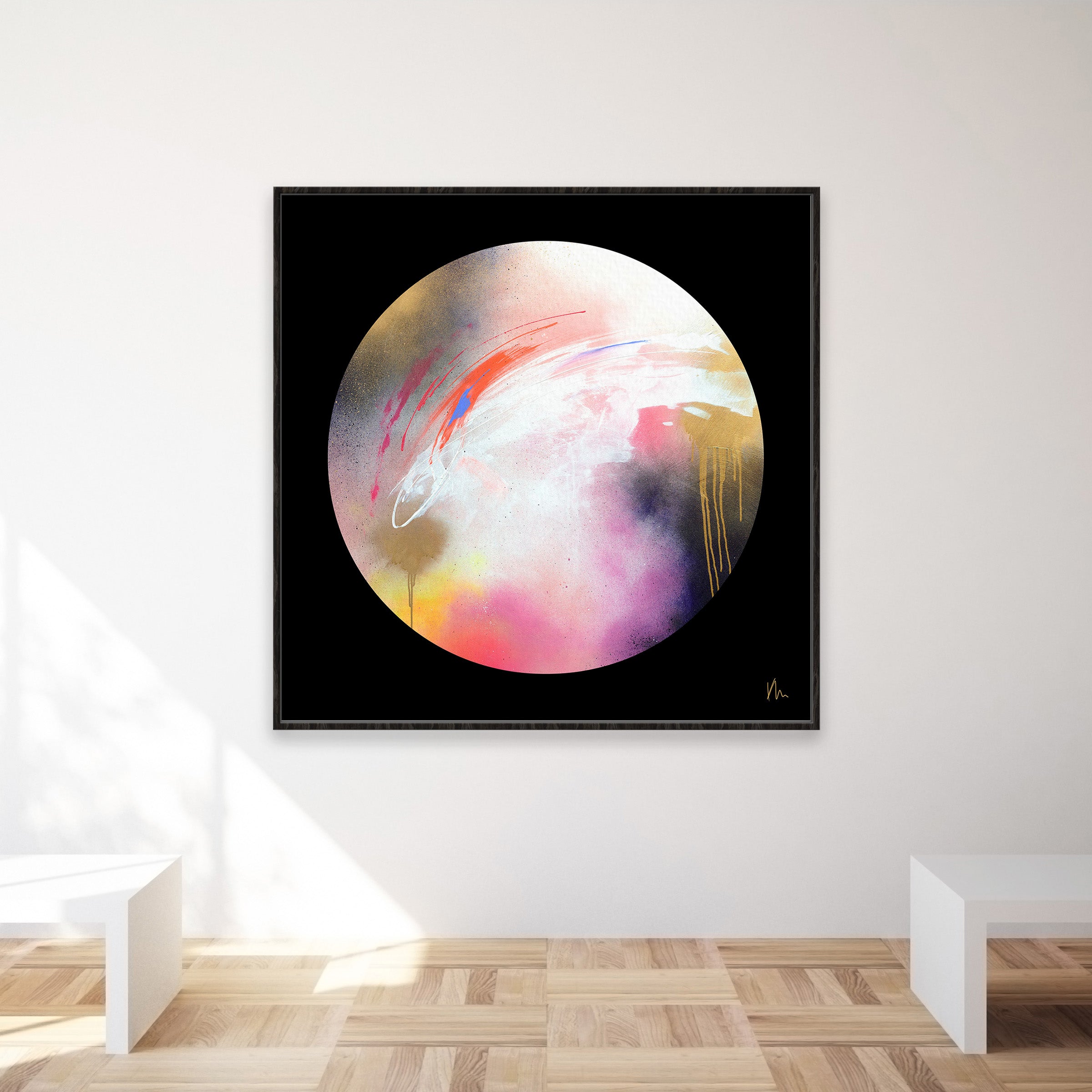 The Dream Starts Here," an abstract painting by Kate Mayer featuring a striking circular multicolored pattern, is elegantly displayed on a minimalist white wall above two white benches.