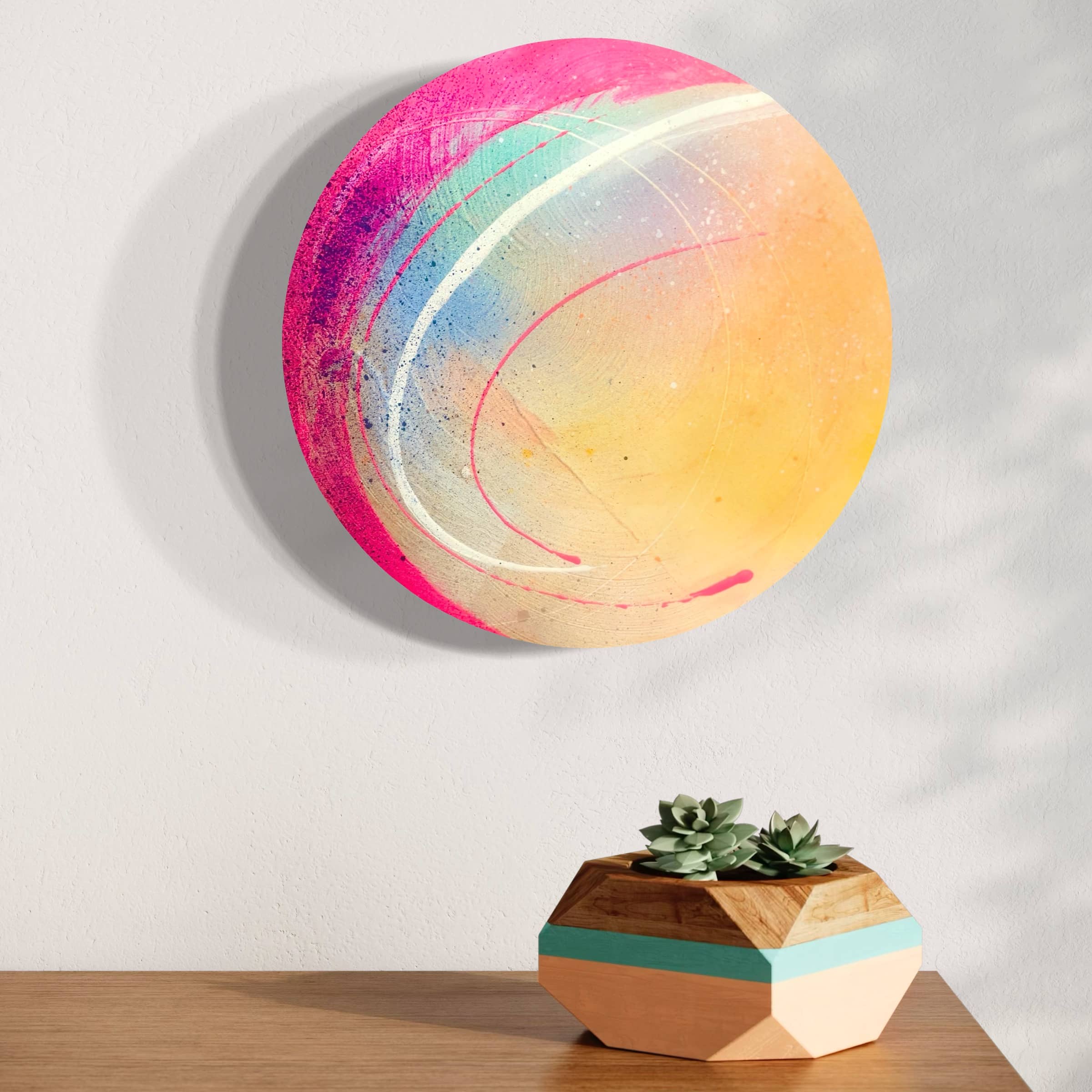 Kate Mayer's "Be Colourful" painting adorns the wall above a geometric wooden plant holder with succulents.