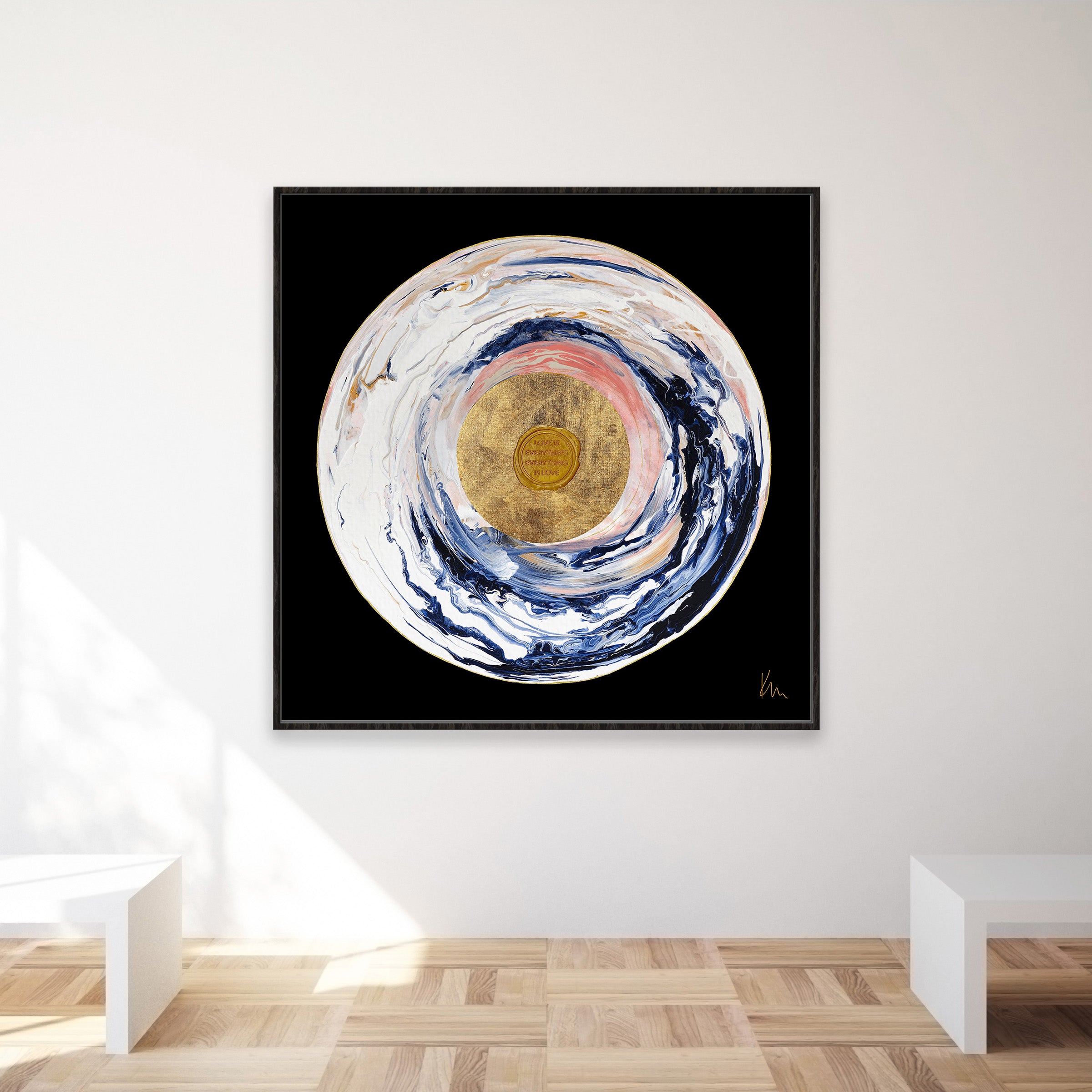 The "Love Sublime" artwork by Kate Mayer, featuring abstract circular patterns in swirling blues, whites, and gold on a black square canvas, adds a touch of elegance to the minimalist room and creates a captivating focal point.