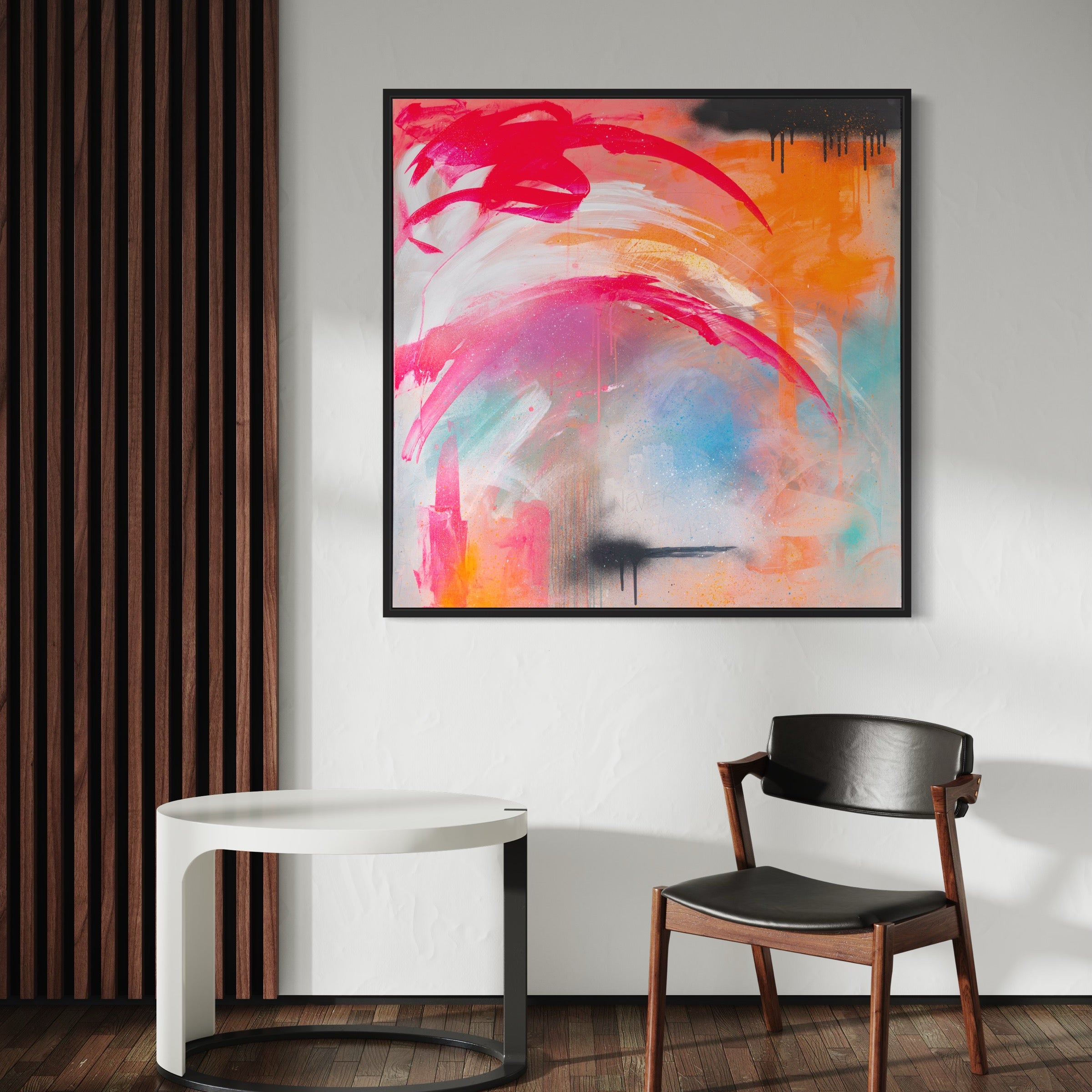 ‘Never Too Much’, an original painting by Kate Mayer, crafted with vibrant pinks, oranges, and blues using acrylic and spray paint, hangs on a wall next to a chair and small table.