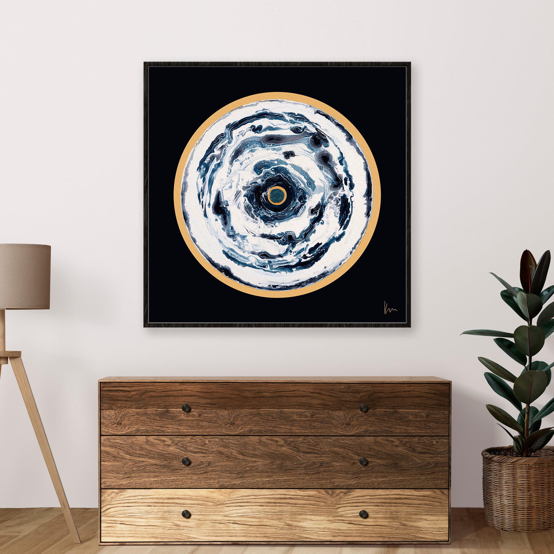 The "Oceans Of Love" painting by Kate Mayer, featuring an abstract swirl of black, white, and gold hues, adorns a wooden dresser in a minimalist room setting, infusing the space with artistic elegance and enhancing its serene atmosphere.
