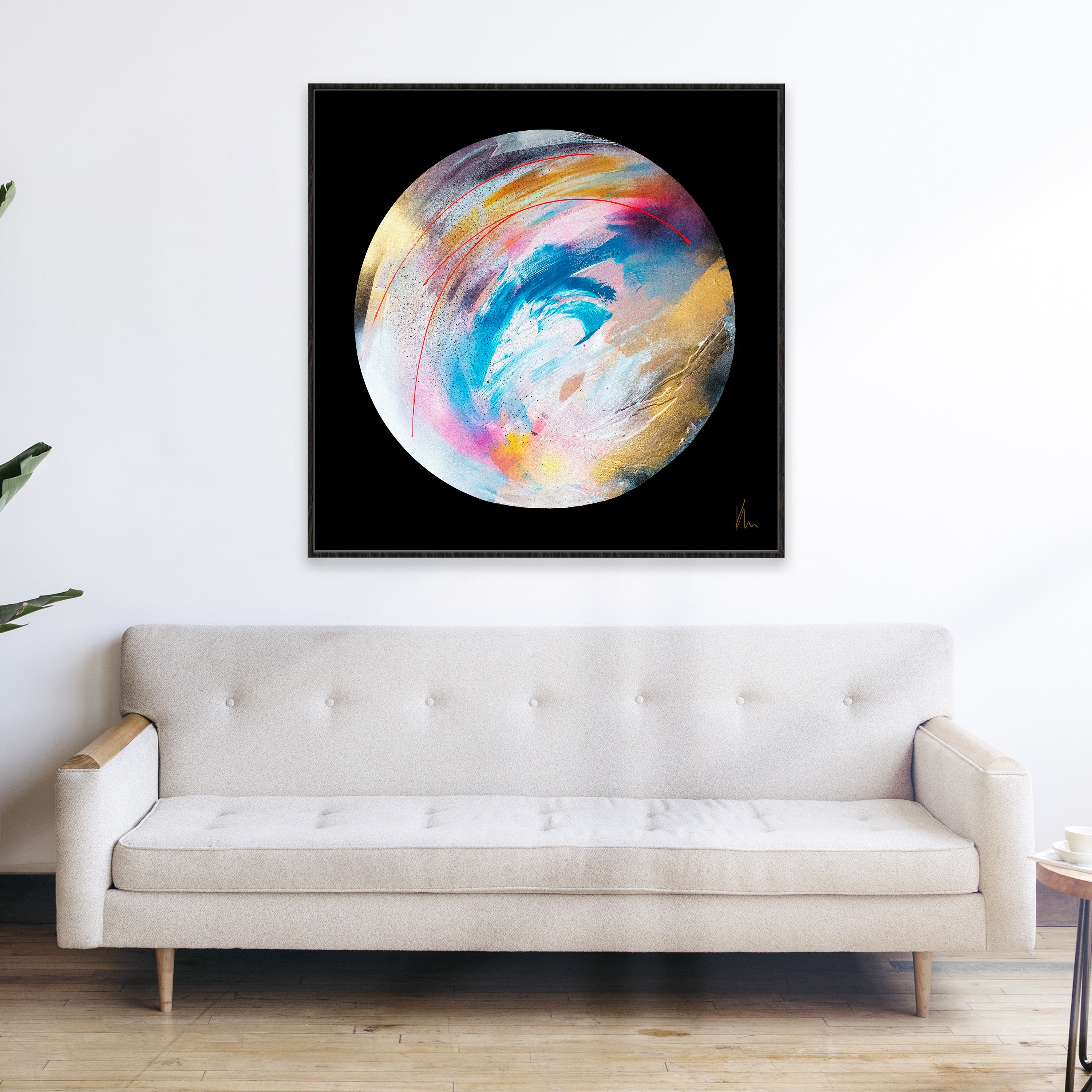 A modern living room with a beige sofa and a framed abstract painting, "Speak Your Truth" by Kate Mayer, featuring swirling colors on a black background above the sofa completes the contemporary description.