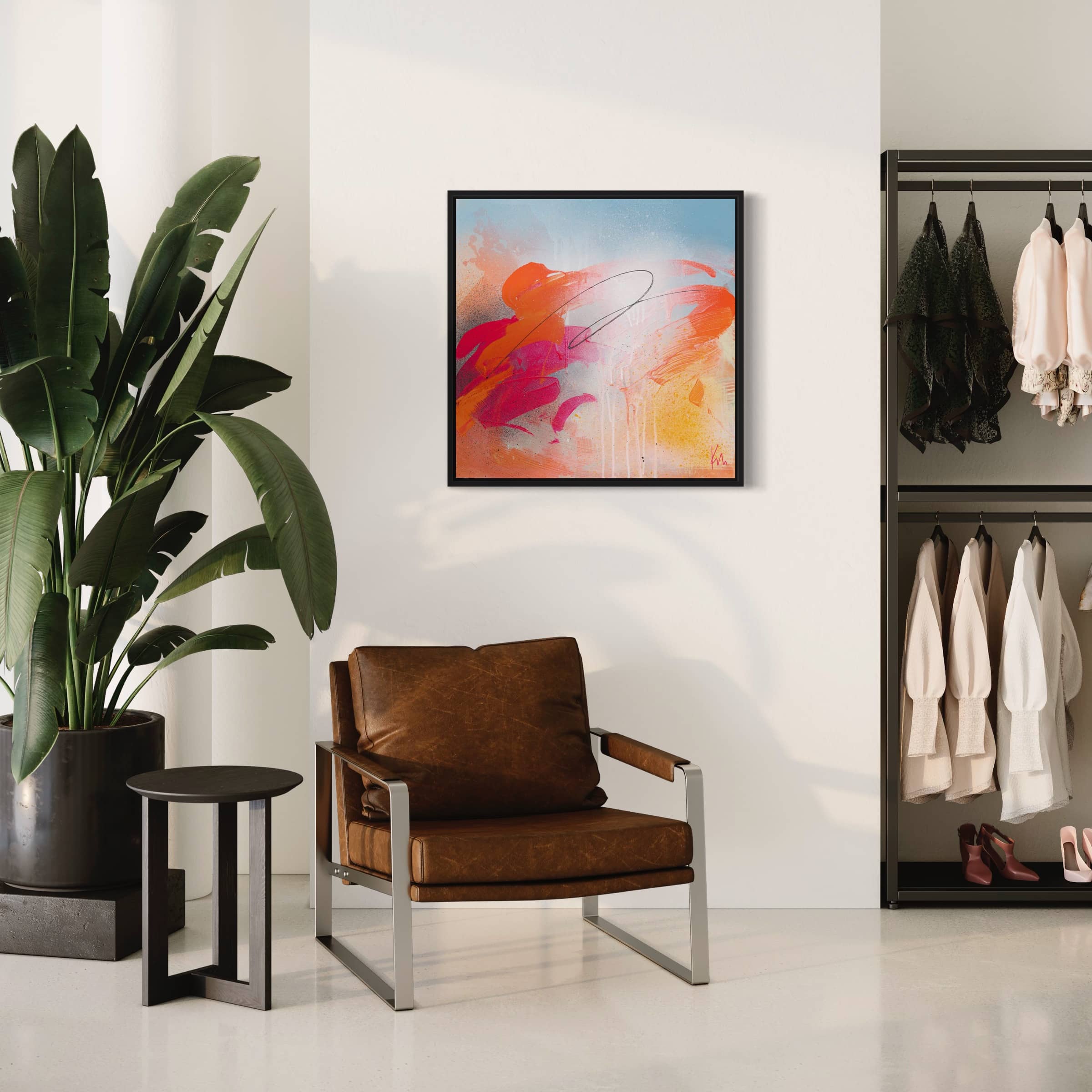 A modern room showcases a brown chair, side table, and the captivating "Dance With Me" original painting by Kate Mayer in acrylic on canvas. Next to this artistic masterpiece stands a large plant and a clothing rack that is beautifully adorned with elegant dresses.