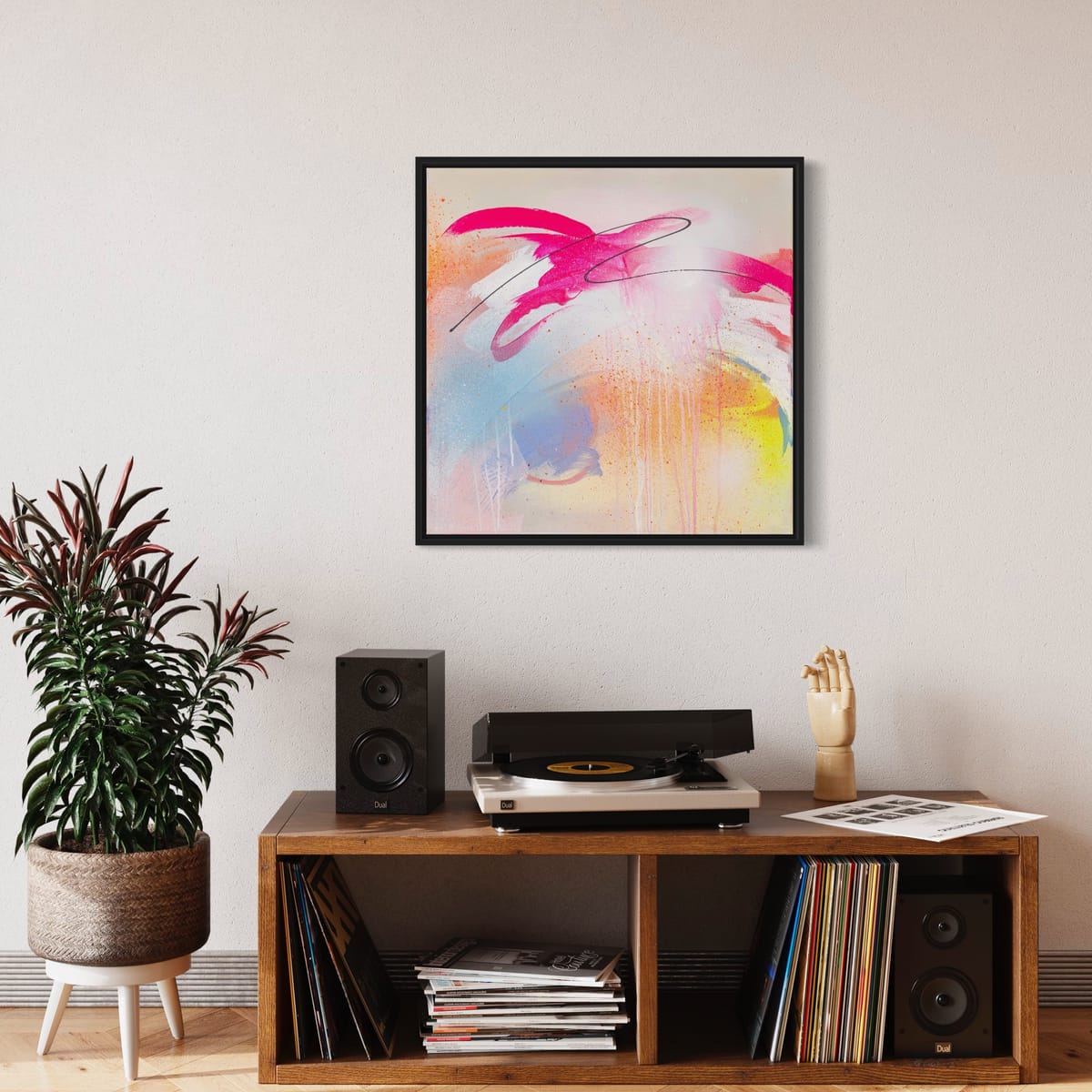 A modern living room highlights the "Hell Yeah" original painting by Kate Mayer, accented with a record player, speakers, and a potted plant on a wooden console.