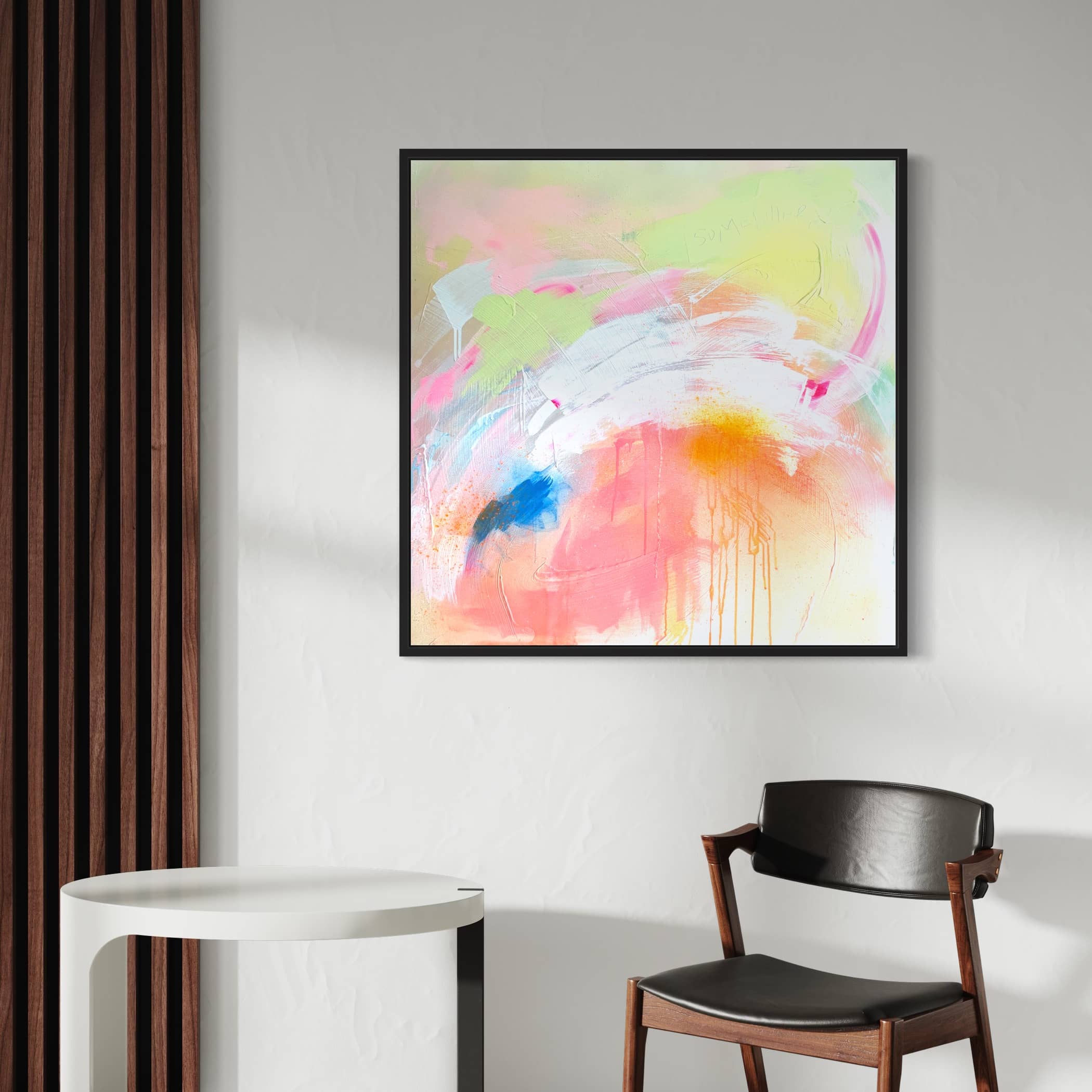 The Pure Joy - Original Painting by Kate Mayer, featuring modern abstract colors and created with acrylic and spray paint on canvas, is framed in a sleek black wooden float frame. It hangs on a white wall above a black chair and a small white round table.