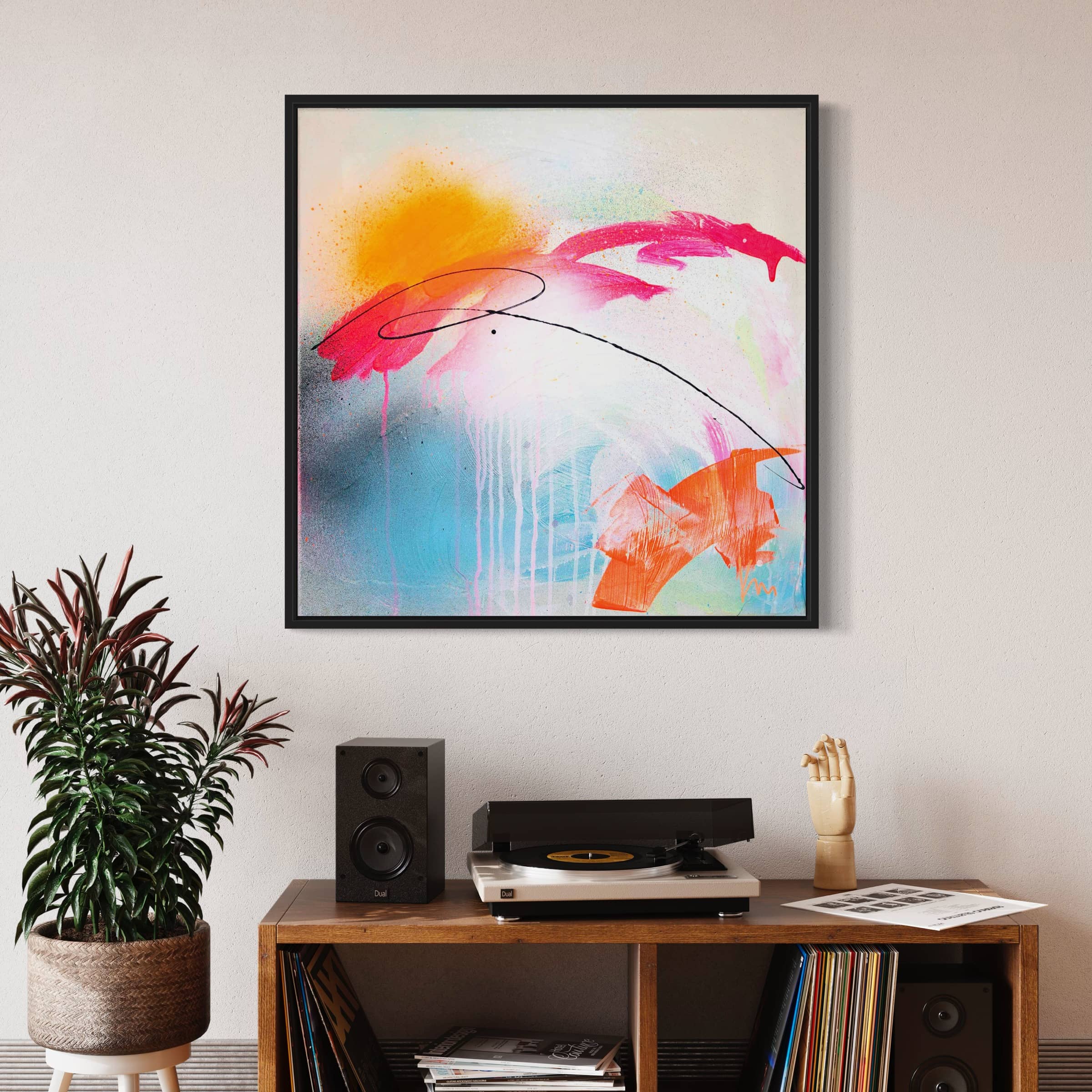 A turntable sits on a shelf with records, accompanied by a small potted plant. Above, the **Rise & Shine Bright - Original Painting** by **Kate Mayer**, featuring vibrant hues of acrylic and spray paint, adds a splash of color to the wall.