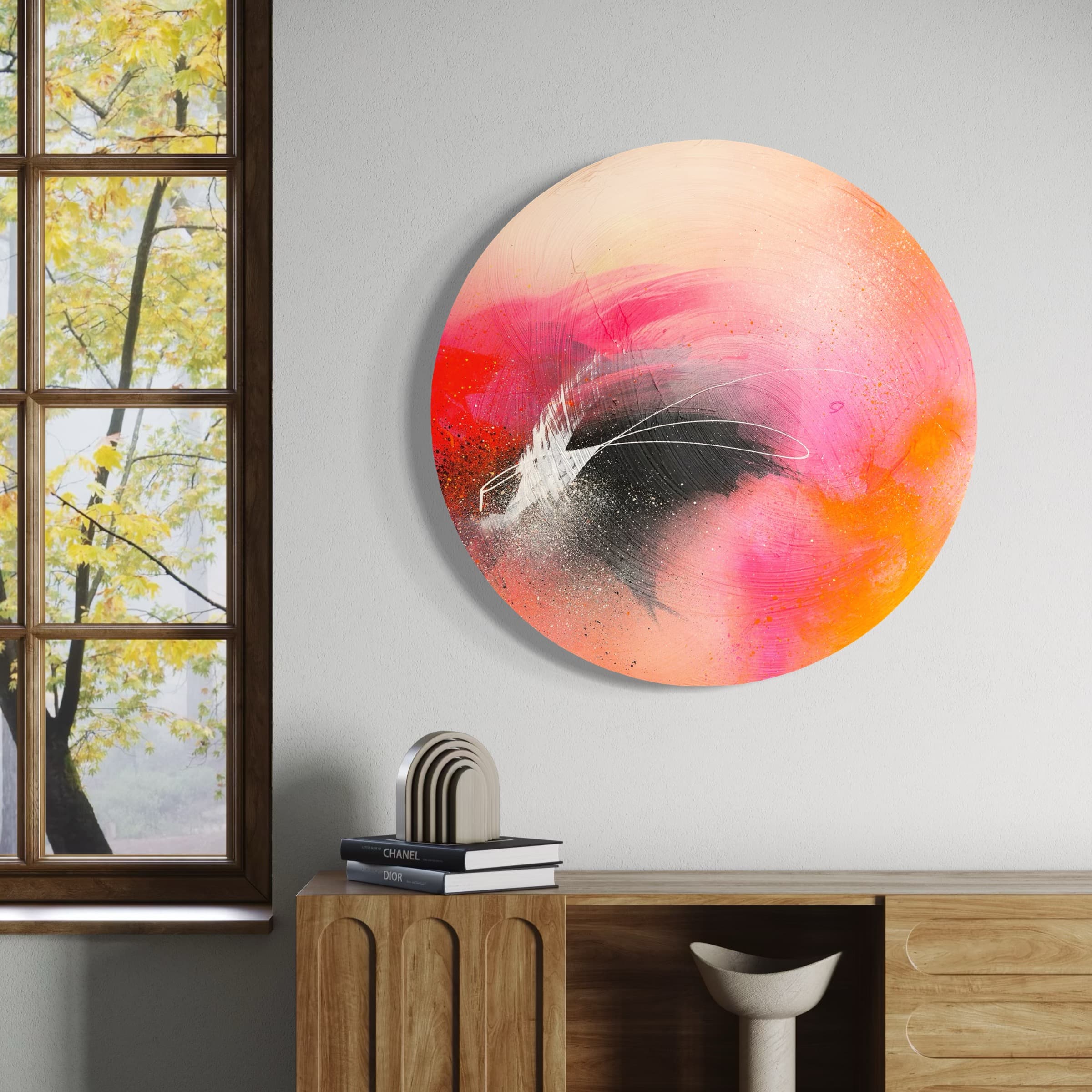 Set The World On Fire" by Kate Mayer: a round painting in pink, orange, black. Beside it, a wooden cabinet and tree view window.