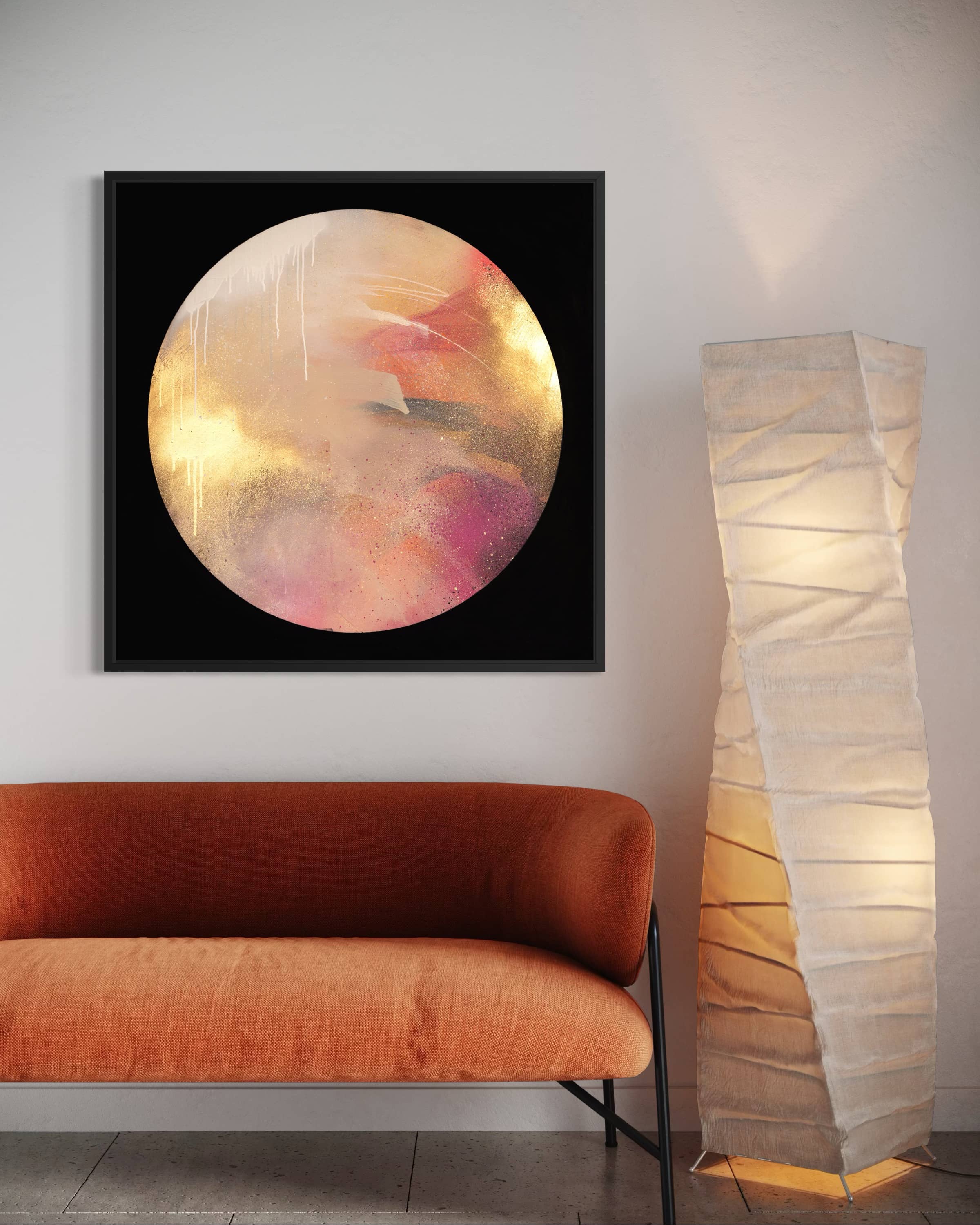 Where Love Lives" by Kate Mayer, with gold and peach hues, hangs above an orange sofa beside a glowing floor lamp.