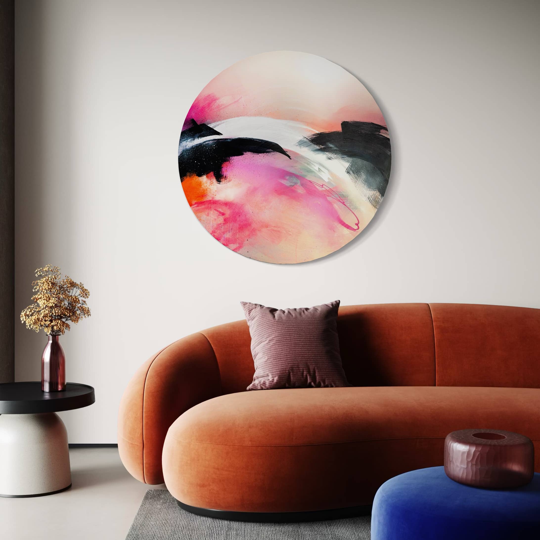 A modern living room with a curved orange sofa, "It's A New Dawn" painting, black side table, and a vase.