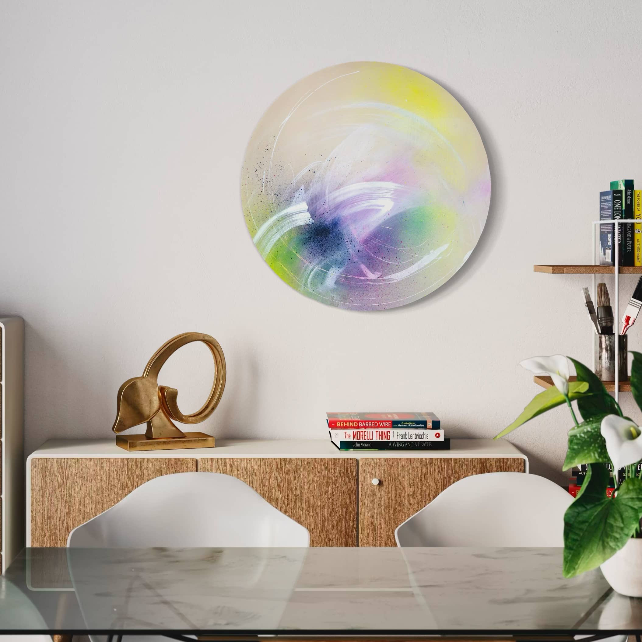 A modern dining area with Kate Mayer's "I Believe In Miracles," a wooden sideboard, sculpture, books, and plants.
