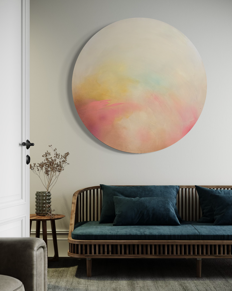 The Afterglow of Connection“ by Kate Mayer, a round pastel artwork in a metal frame above a teal-cushioned sofa.