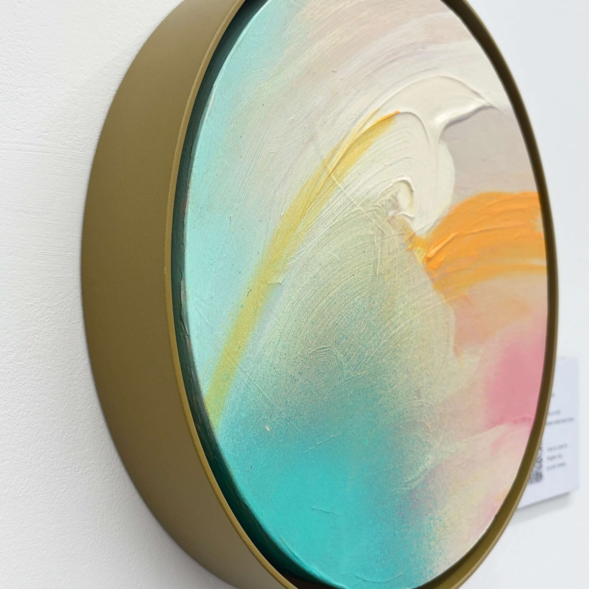 Brighter Day“ by Kate Mayer: Side view of a round abstract with teal, yellow & cream swirls in a metal float frame.