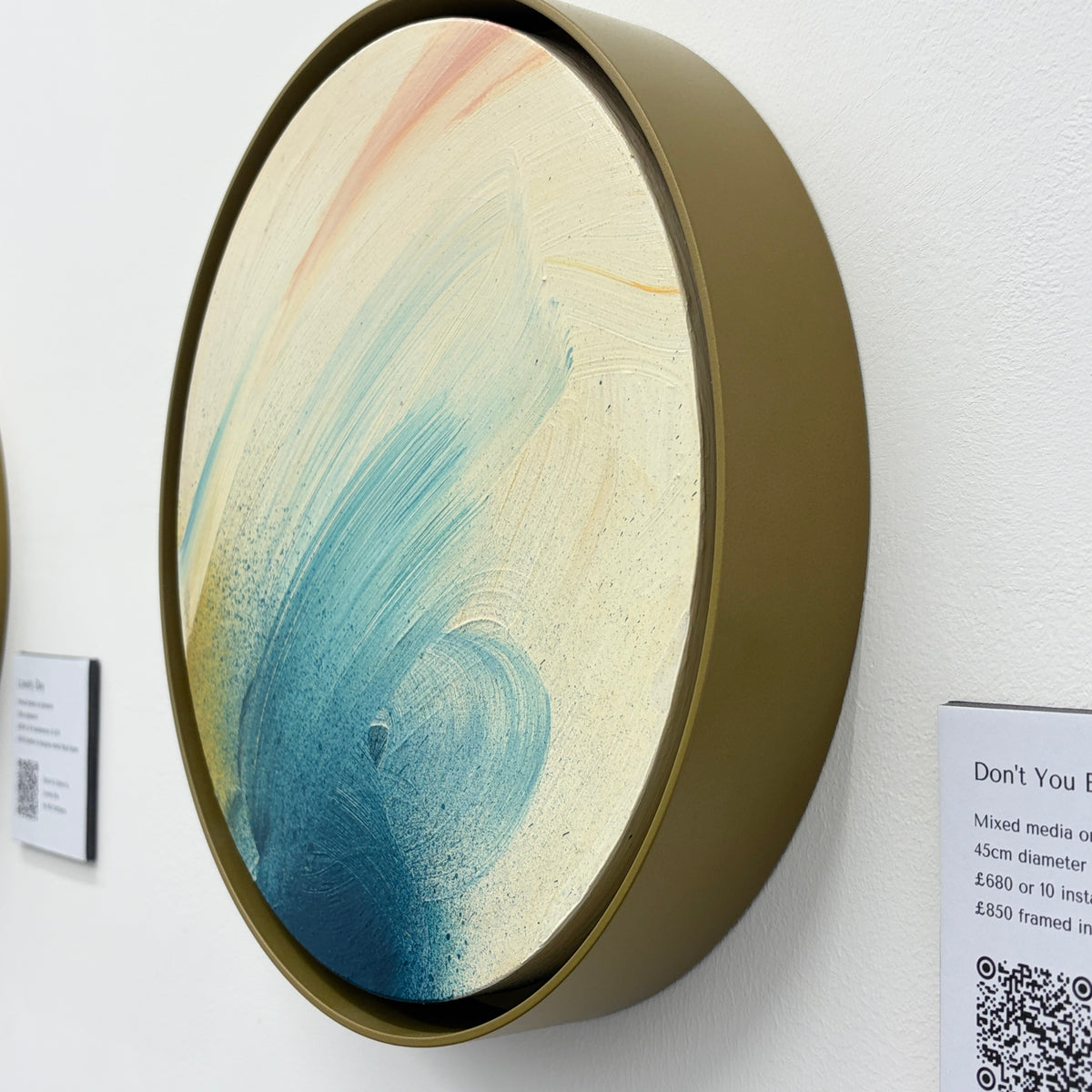Don’t You Every Give Up by Kate Mayer: round abstract painting with blue & peach strokes, in a handmade float frame.