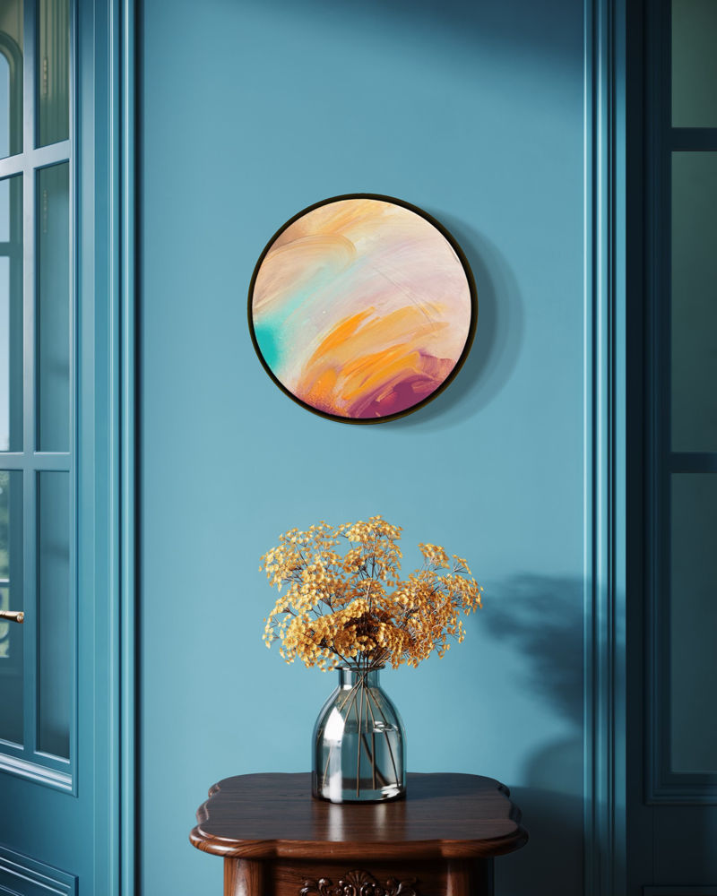 Good Times“ by Kate Mayer—round abstract art in a metal float frame hangs above a table with dried yellow flowers.