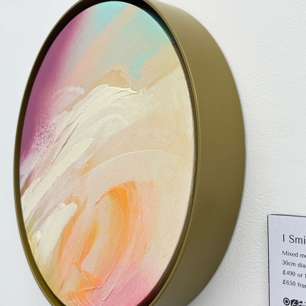 I Smile“ by Kate Mayer: Round acrylic on plywood with pastel swirls, in a handmade metal frame, on white wall.