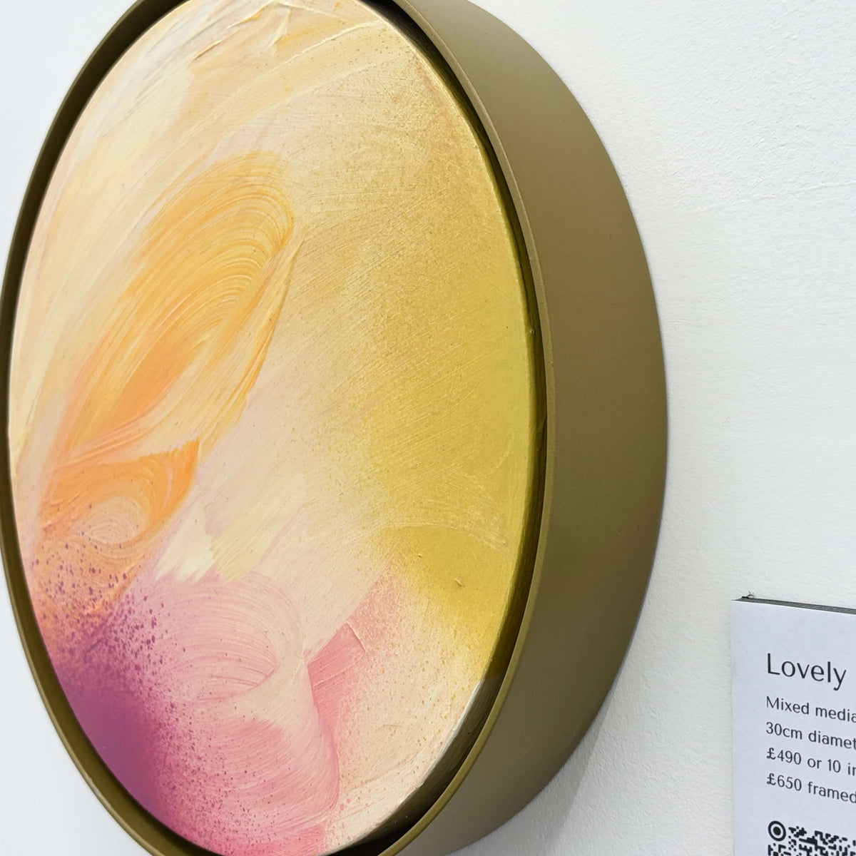 Lovely Day by Kate Mayer: a round abstract in yellow, cream & pink, framed in handmade metal, on a white wall.