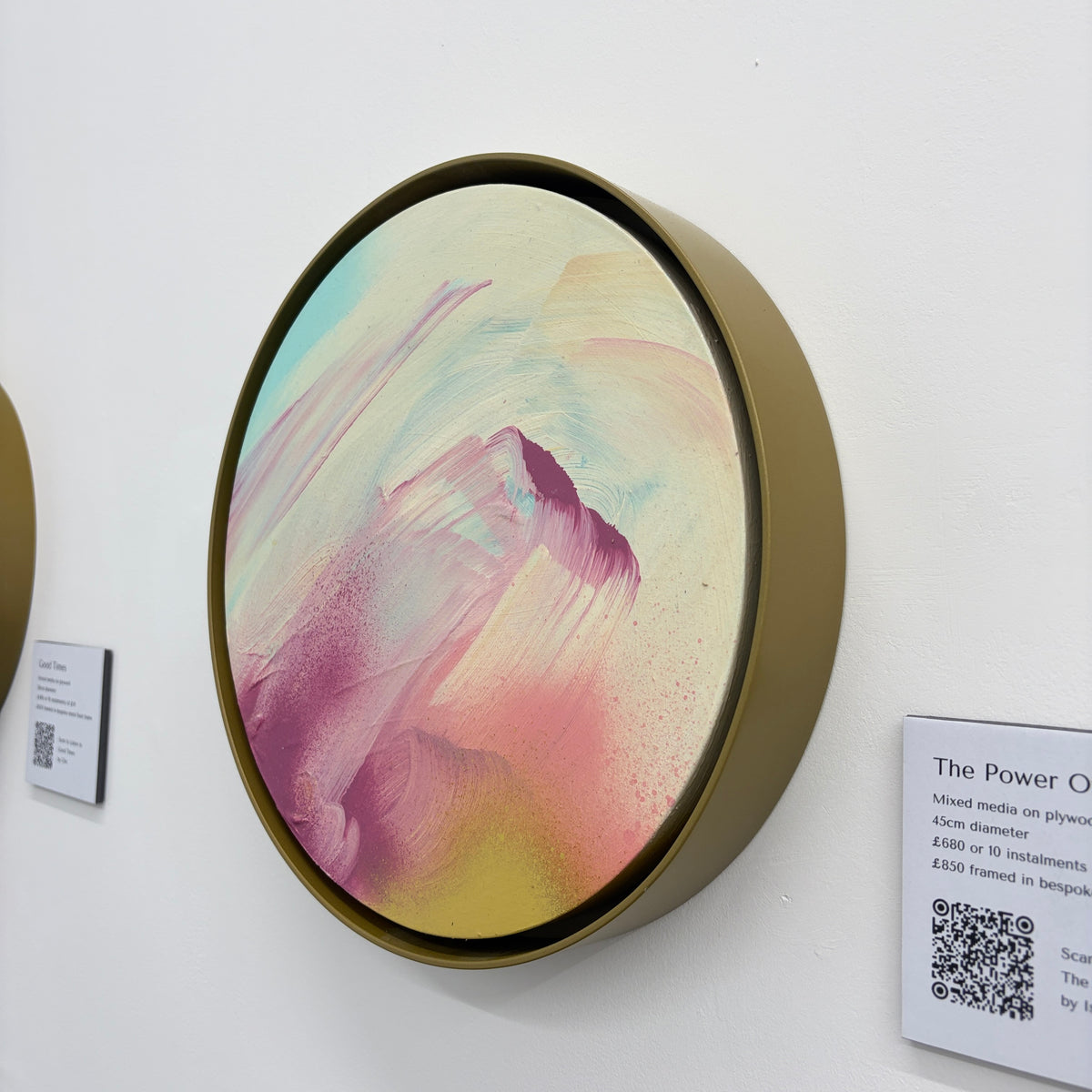 The Power Of One by Kate Mayer: round acrylic on plywood in handmade metal frame, shown on white gallery wall with label.