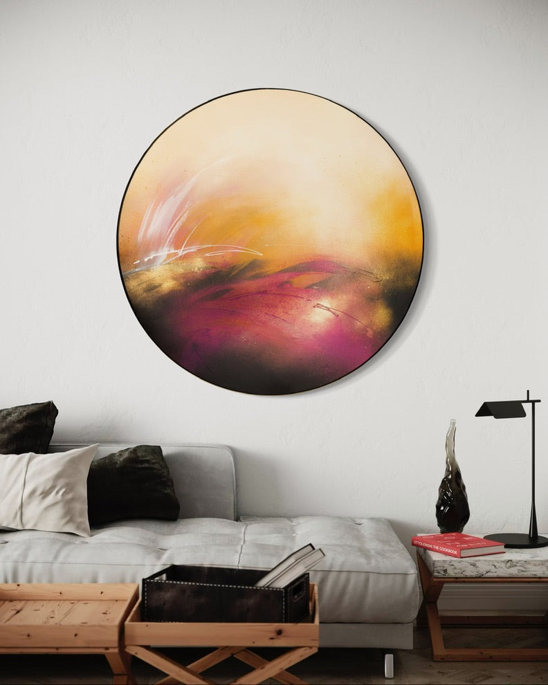 “It’s Alright, I Feel It” by Kate Mayer: round acrylic art in warm tones, above a modern sofa with pillows and decor.
