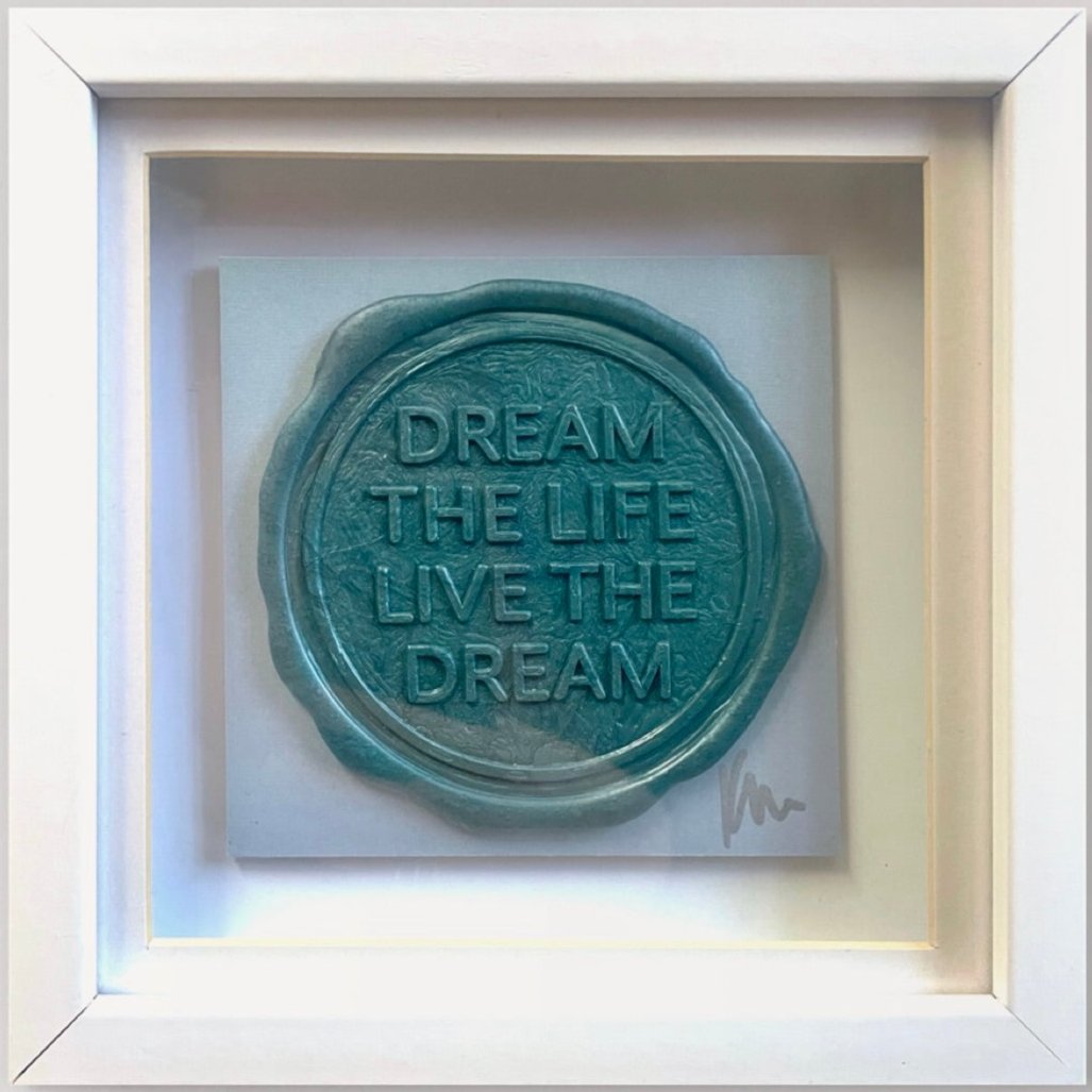 A framed artwork titled "Sealed Intention to Live The Dream" by Kate Mayer, featuring the phrase "DREAM THE LIFE LIVE THE DREAM" in teal against a light grey background and signed by the artist.