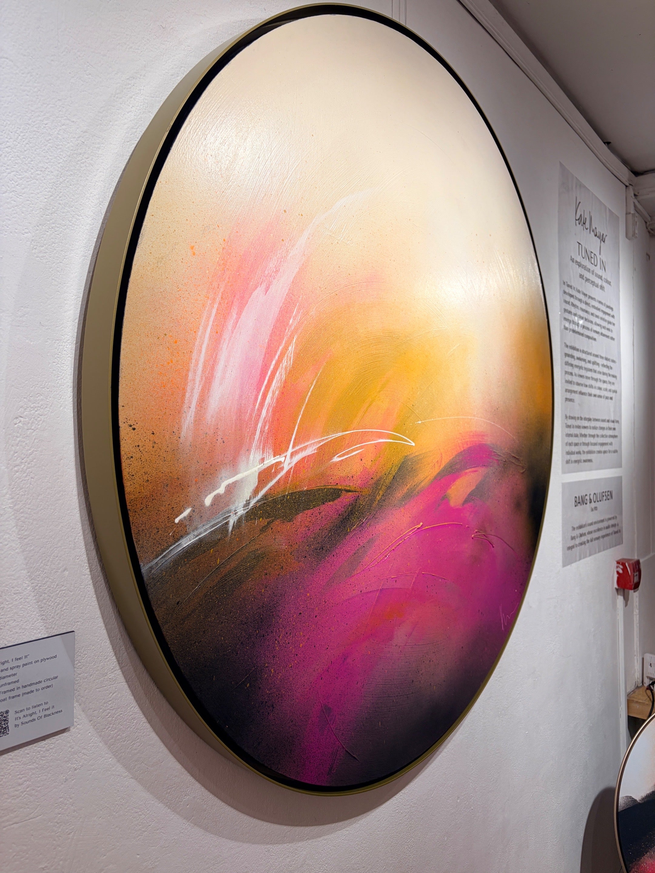 It’s Alright, I Feel It" by Kate Mayer: a round abstract acrylic painting with swirling pink, orange, yellow, and white.