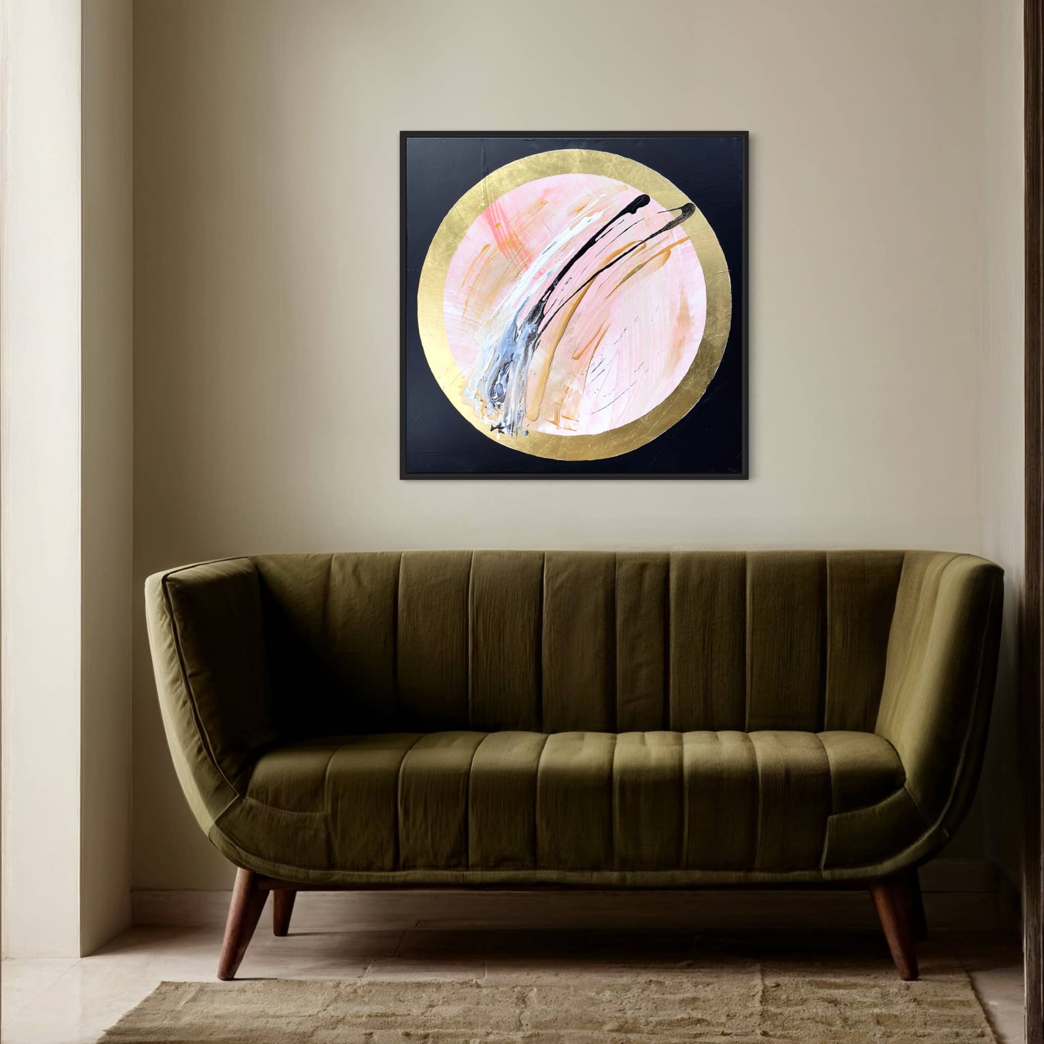 A green velvet couch sits in front of a light tan wall adorned with "Let's Go Beyond," a circular abstract painting by Kate Mayer, framed in gold and black, featuring intricate acrylic and gold leaf details.