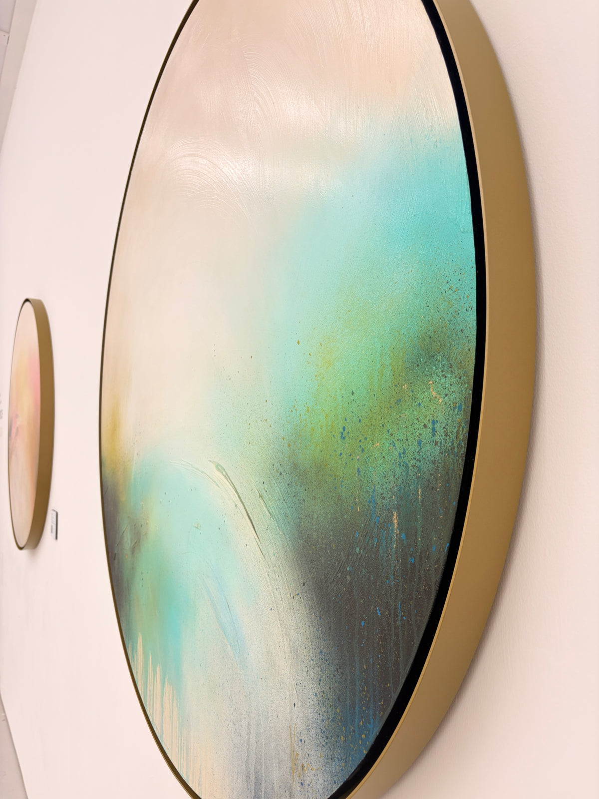The Afterglow of Stillness“ by Kate Mayer, acrylic on plywood, shows teal, black & cream swirls in a gold frame.