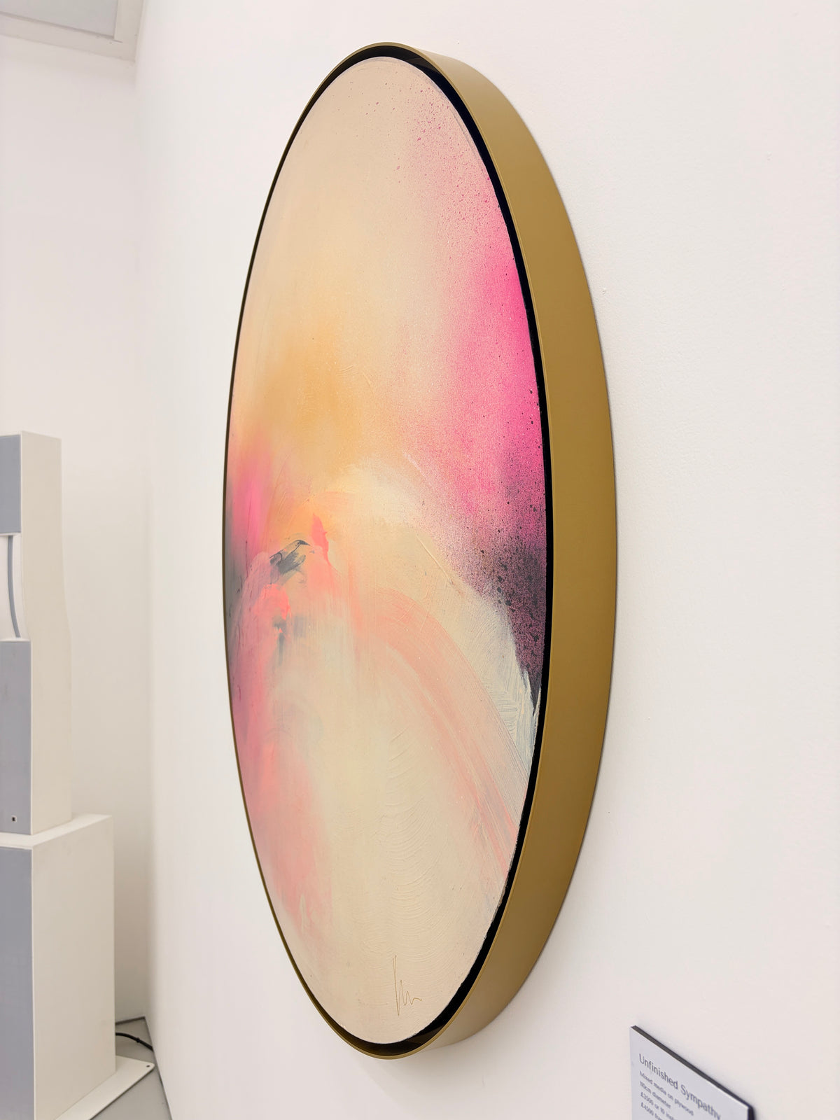 Unfinished Sympathy“ by Kate Mayer: oval abstract in pink, peach, cream tones, framed and displayed with sculpture.