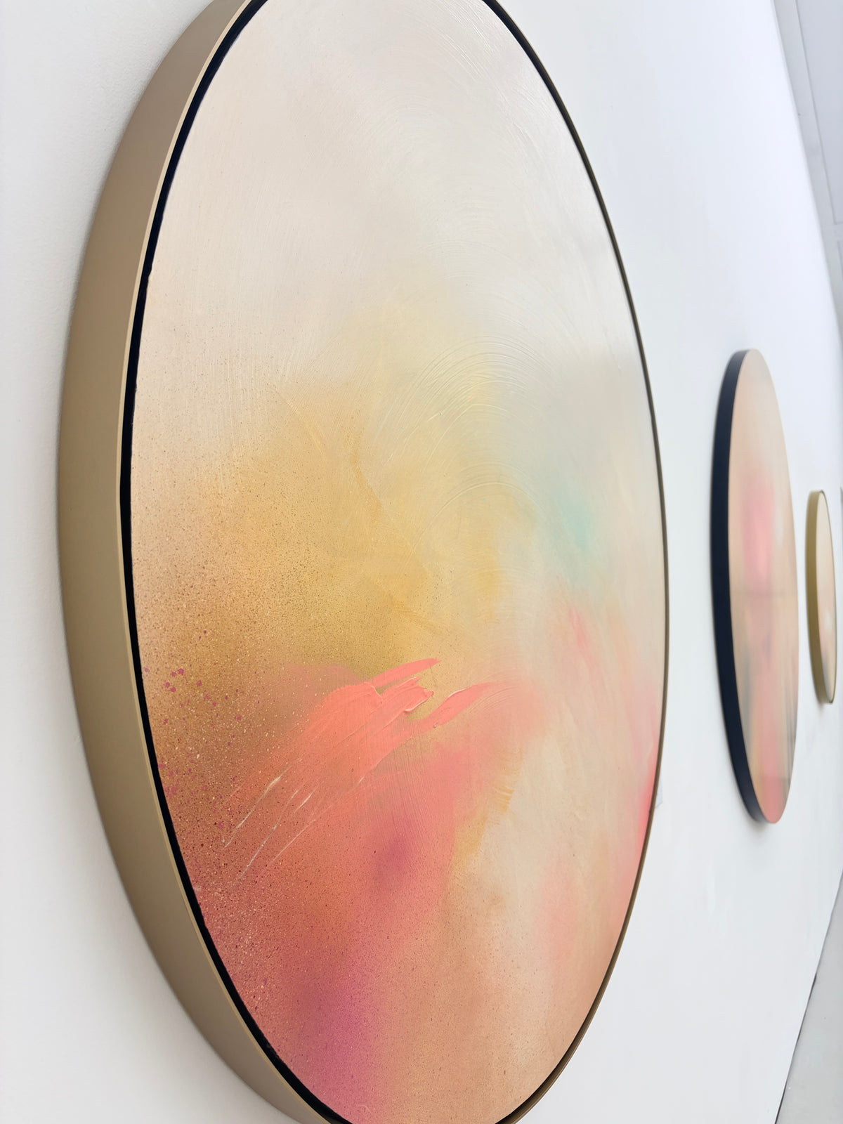 The Afterglow of Connection“ by Kate Mayer: three pastel abstract paintings in a metal float frame on a white wall.