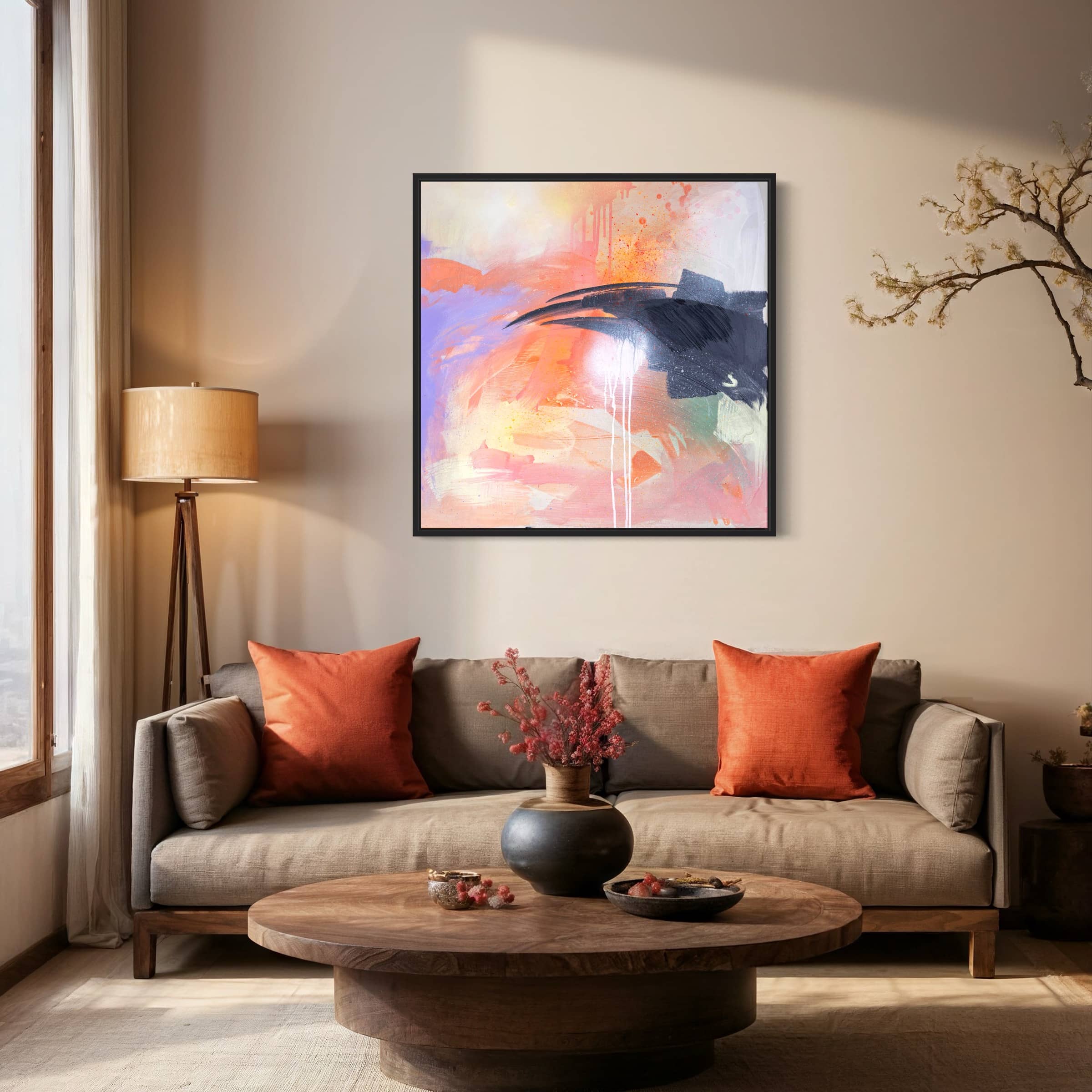 A cozy living room with a beige sofa, orange pillows, a round wooden table, and "Beneath The Surface," an original painting by Kate Mayer, adorning the wall.