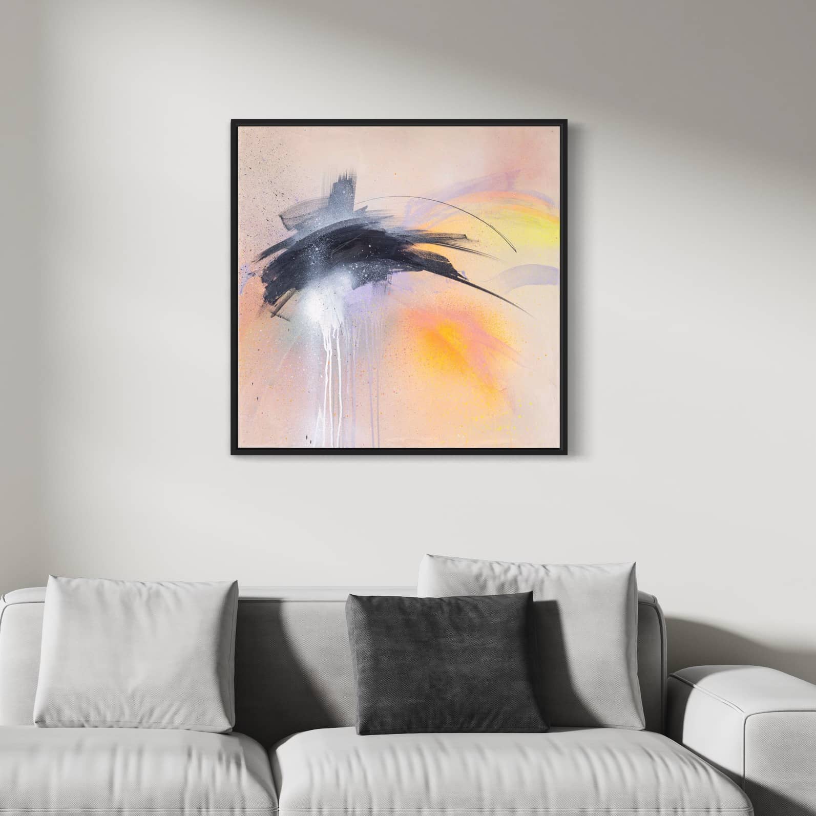 Kate Mayer's original painting, "That Moment On Black Sand Beach," framed in black, adorns the wall above a white couch with grey and white cushions in a minimalistic living room setting.