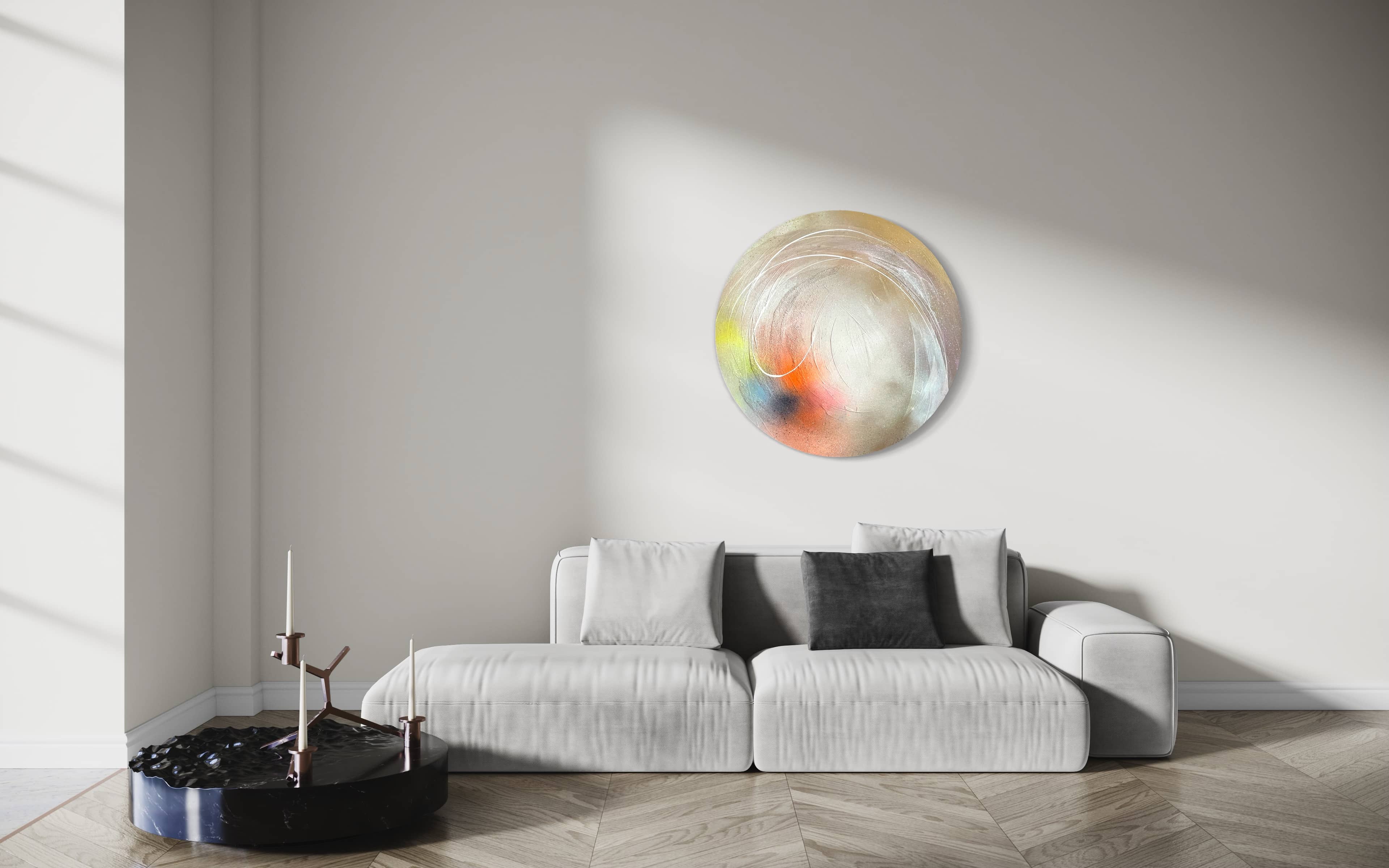 Minimalist living room featuring a light grey sofa, black coffee table, and "The Time Is Now" original painting by Kate Mayer on a white wall; sunlight casting shadows.