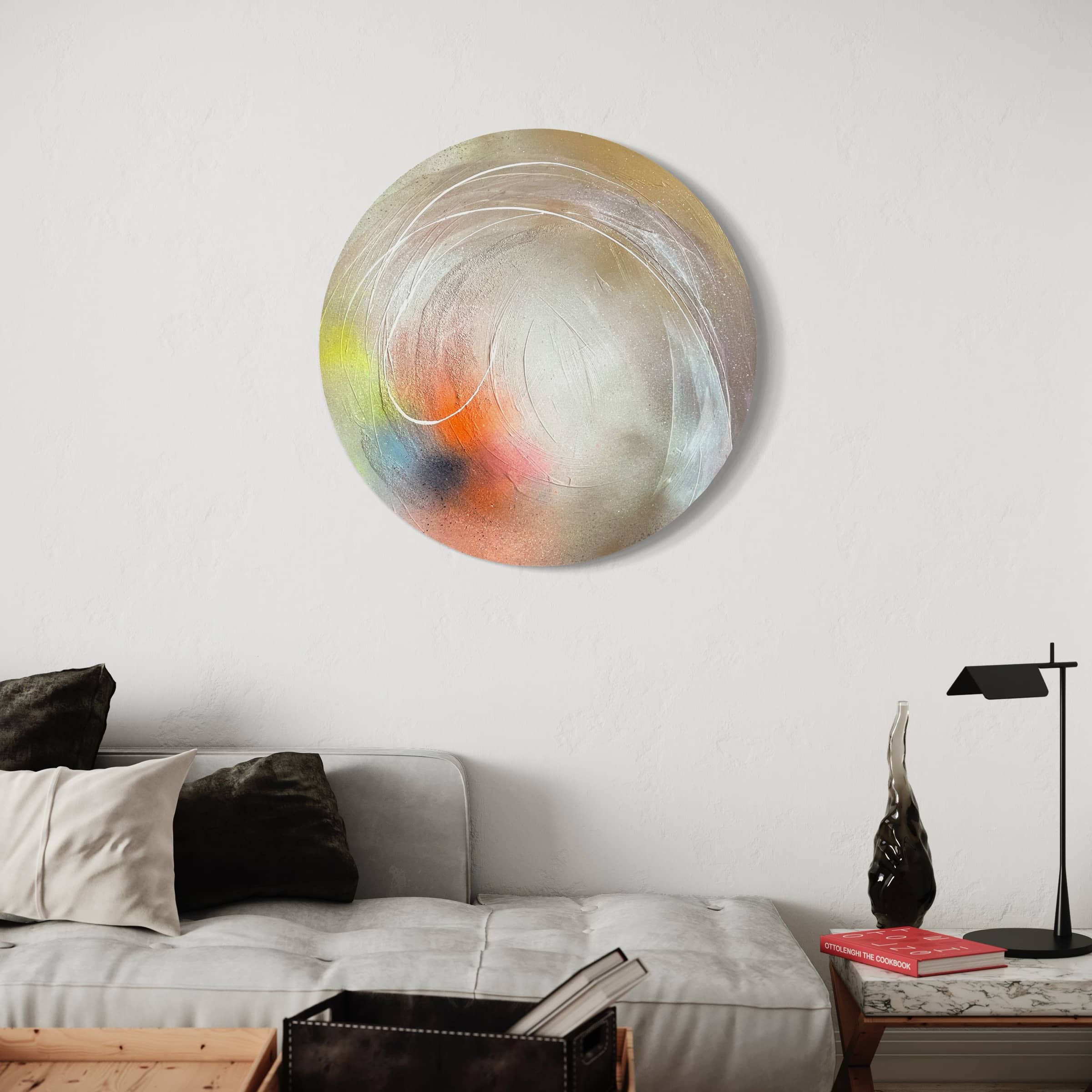 Modern living room with "The Time Is Now," an original abstract painting by Kate Mayer, featuring acrylic diamond dust on the white wall, a gray sofa adorned with black and white pillows, and a side table stacked with books.