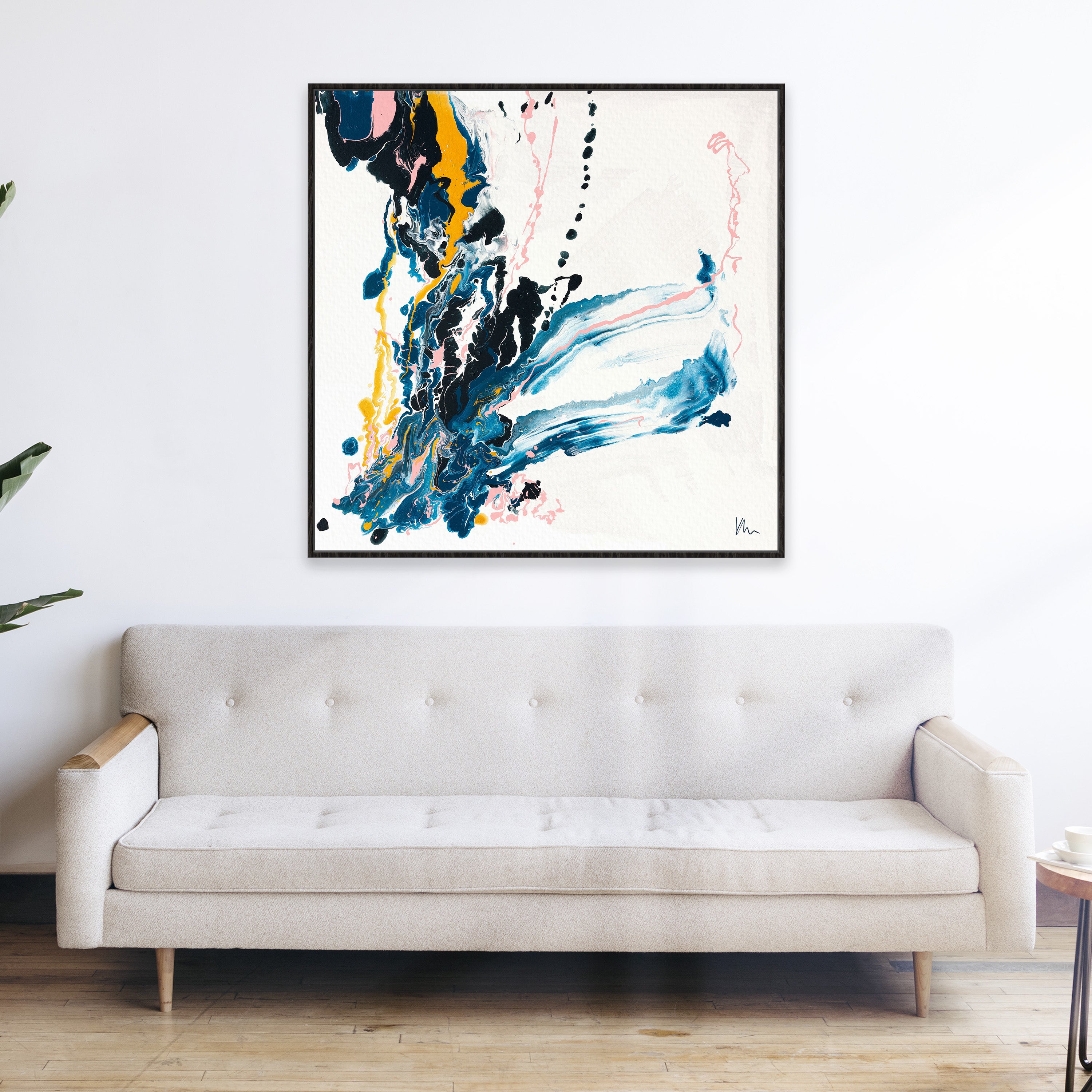 Kate Mayer's "Emerging," a modern abstract painting symbolizing transformation with bold black, blue, and yellow strokes, hangs above a beige sofa in a minimalist living room.