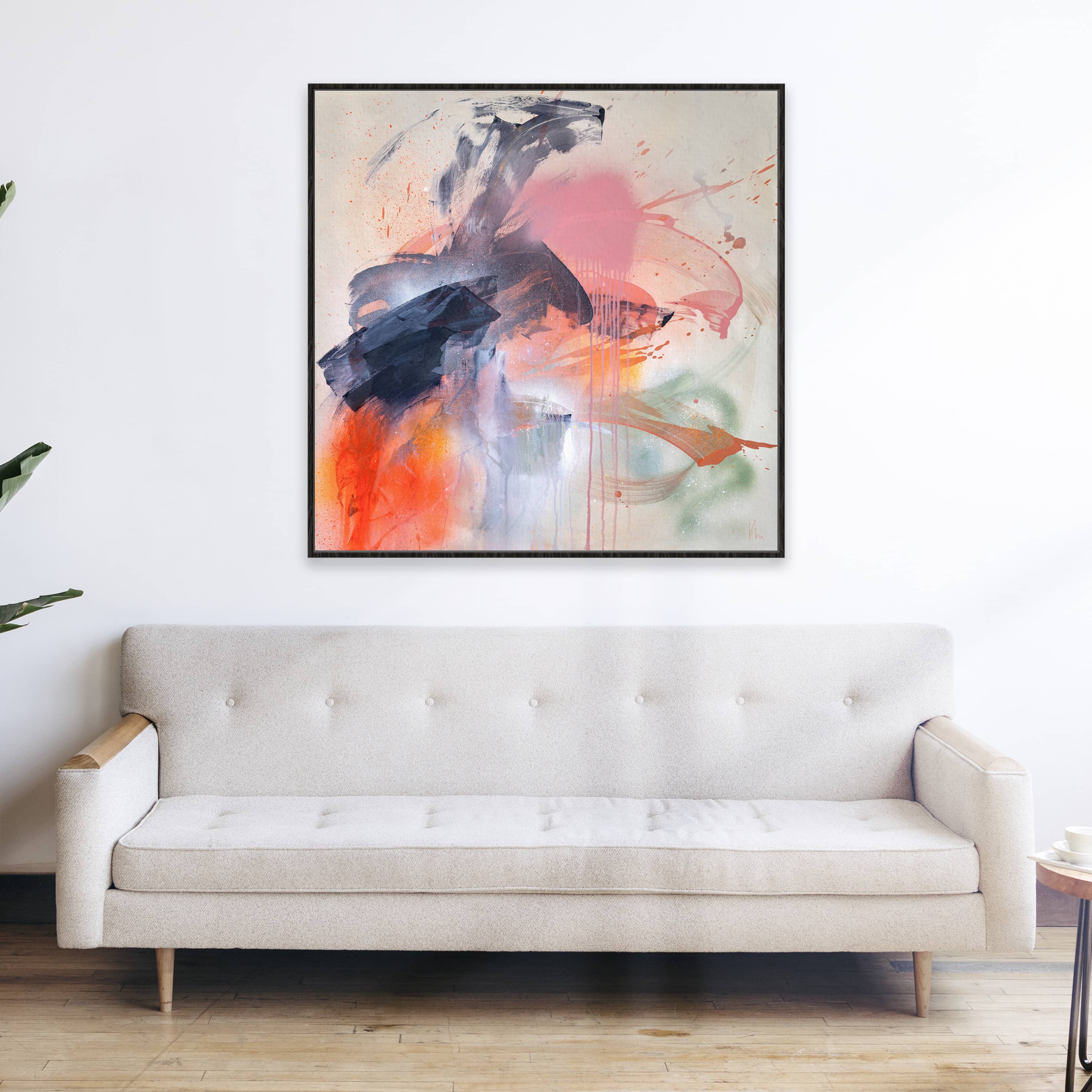 The "Fire And Ice" abstract painting by Kate Mayer features splashes of blue, pink, and orange above a beige sofa in a minimalistic room. The vibrant colors convey inner strength and personal power, making it an inspiring focal point.