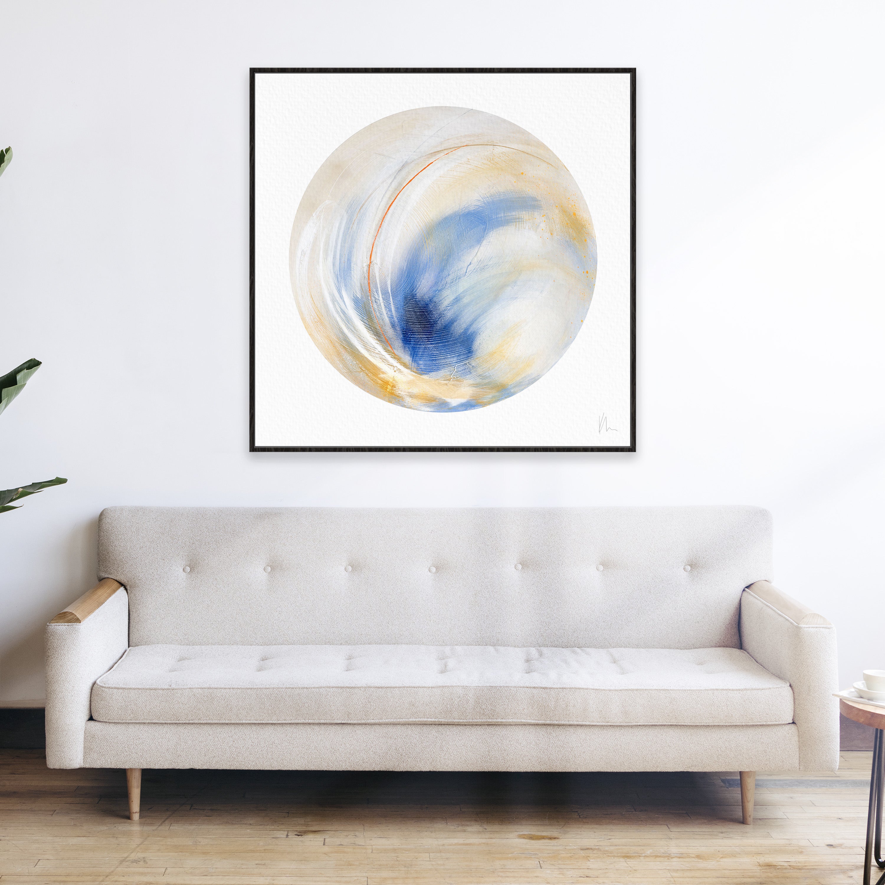 A minimalist living room featuring the Kate Mayer "Go Your Own Way" sofa in light beige showcases individuality, enhanced by abstract circular artwork in blue and gold hues displayed above.