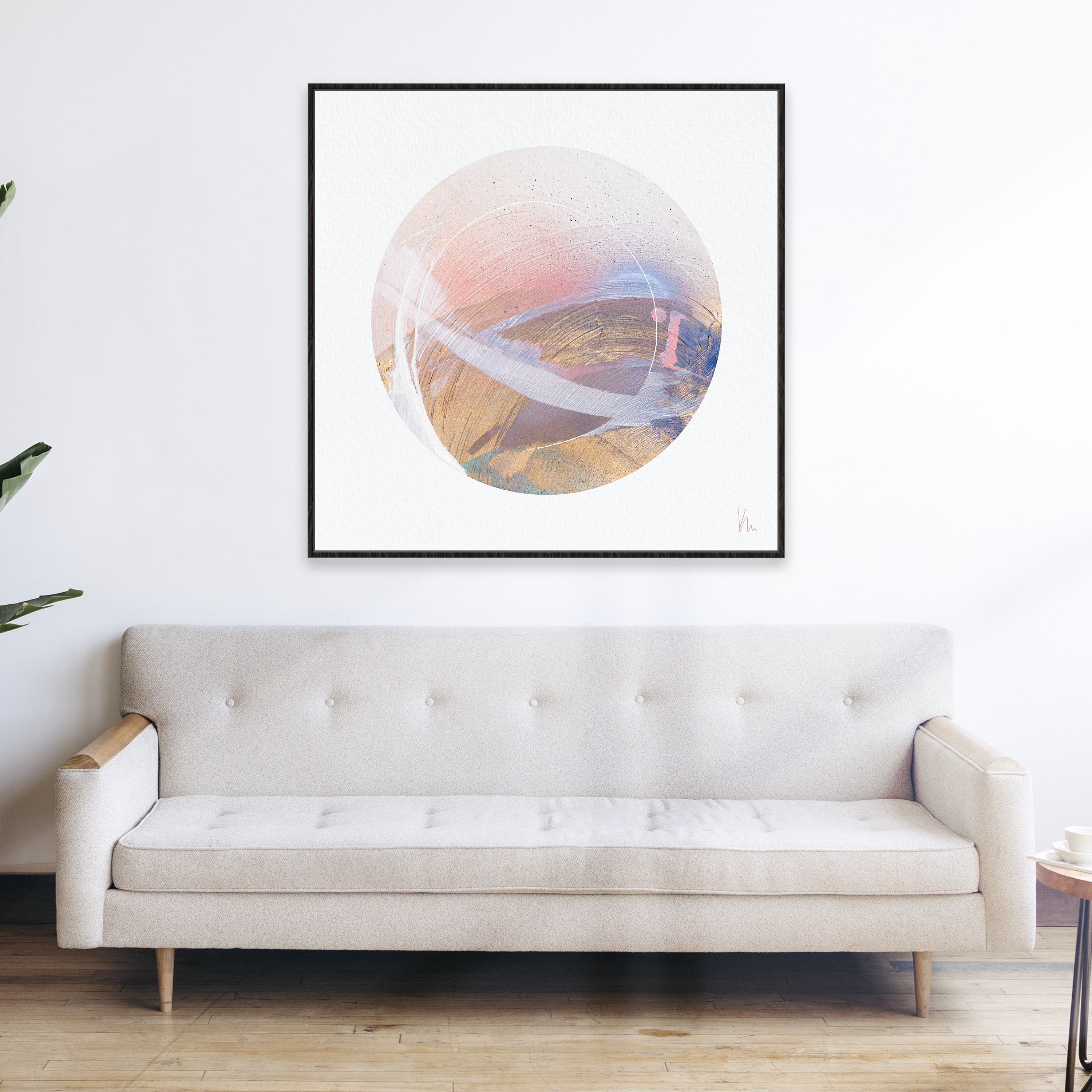 A minimalist living room featuring the "Just Be" beige sofa by Kate Mayer and abstract circular art in pink, white, and brown tones on the wall creates a space for mindfulness and inner reflection.