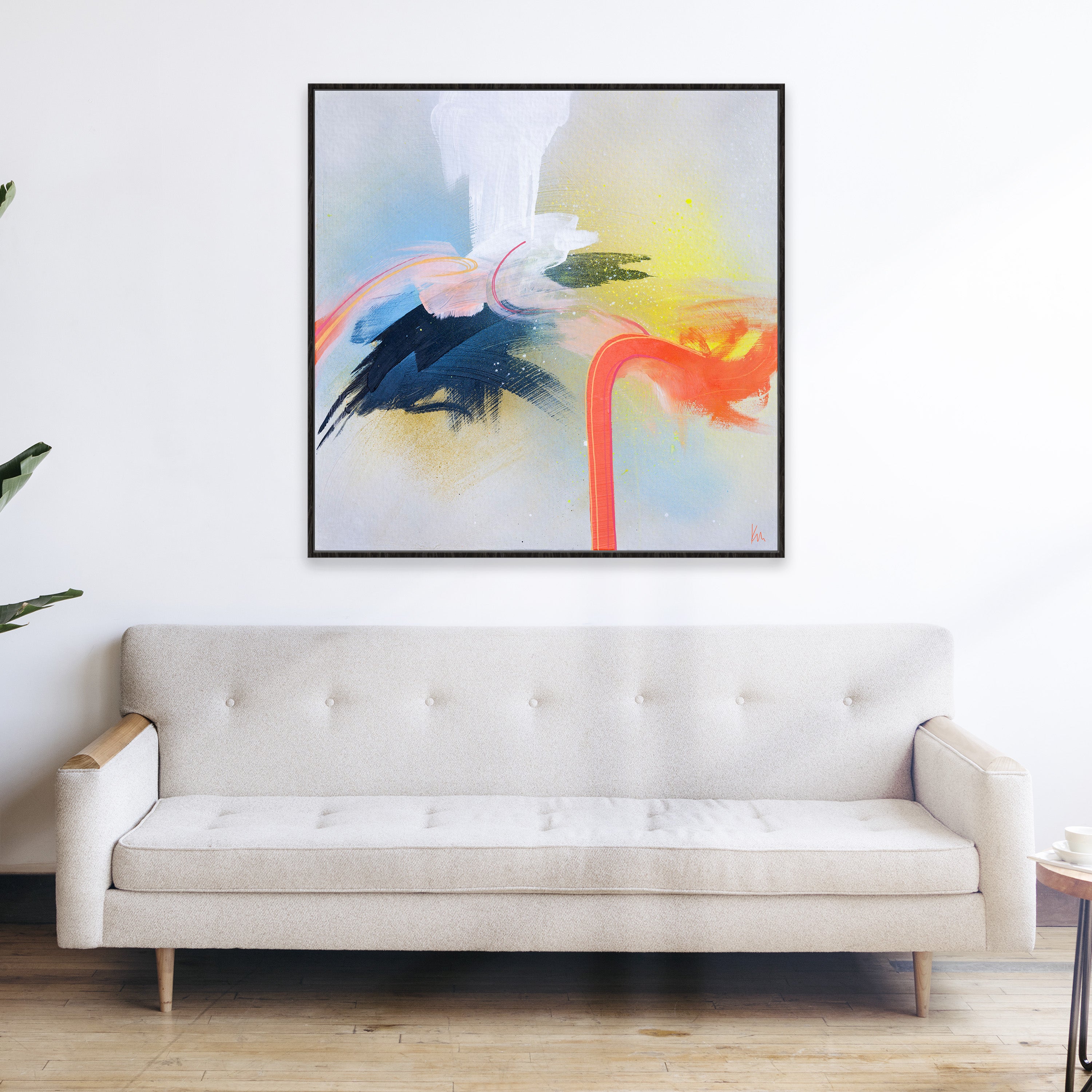 The Miami Flamingo by Kate Mayer, an abstract painting with vibrant colors, graces the wall above a beige sofa. Its blend of blue, orange, and white hues dynamically captures attention and adds a touch of modern elegance to any living space.