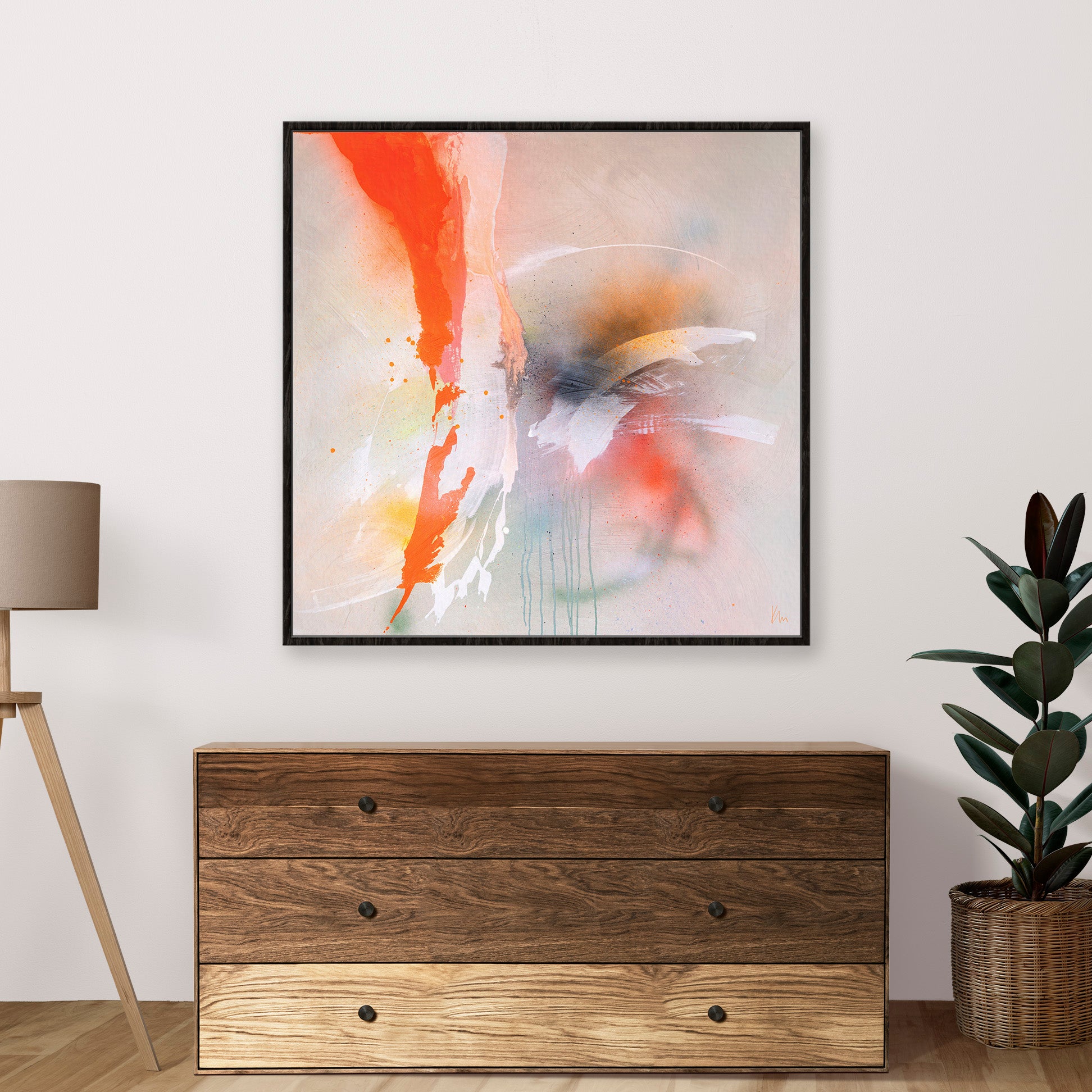 Rainbow Falls, an abstract painting by Kate Mayer featuring vibrant reds, oranges, and whites, is displayed above a wooden dresser. The dresser is situated next to a lamp and a potted plant in a modern room setting.