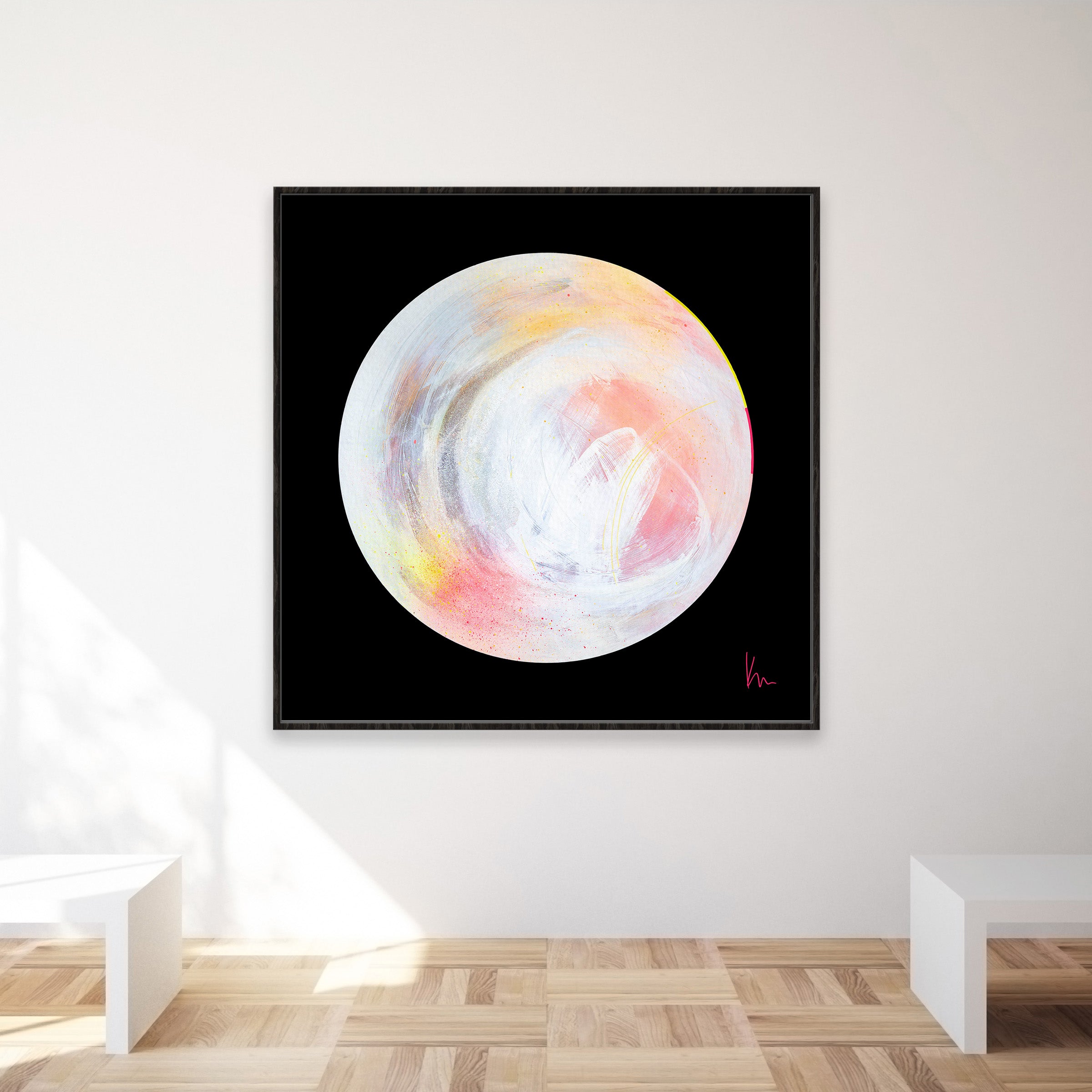 The abstract painting titled "The Time Is Now" by Kate Mayer features a light-colored, swirled circle on a black background. It is displayed in a modern room with wooden flooring and white benches.