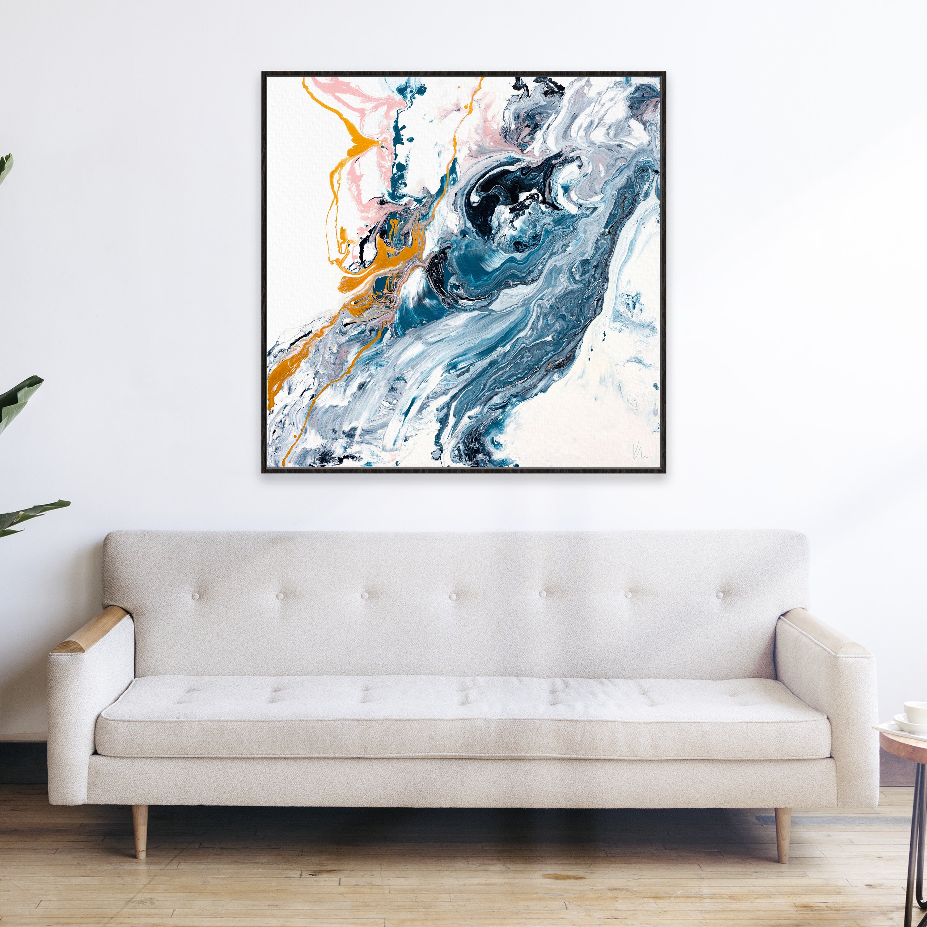 Modern living room with a beige tufted sofa and Kate Mayer's "Undercurrent," a large abstract painting featuring swirls of blue, white, and gold, hanging on the wall above.