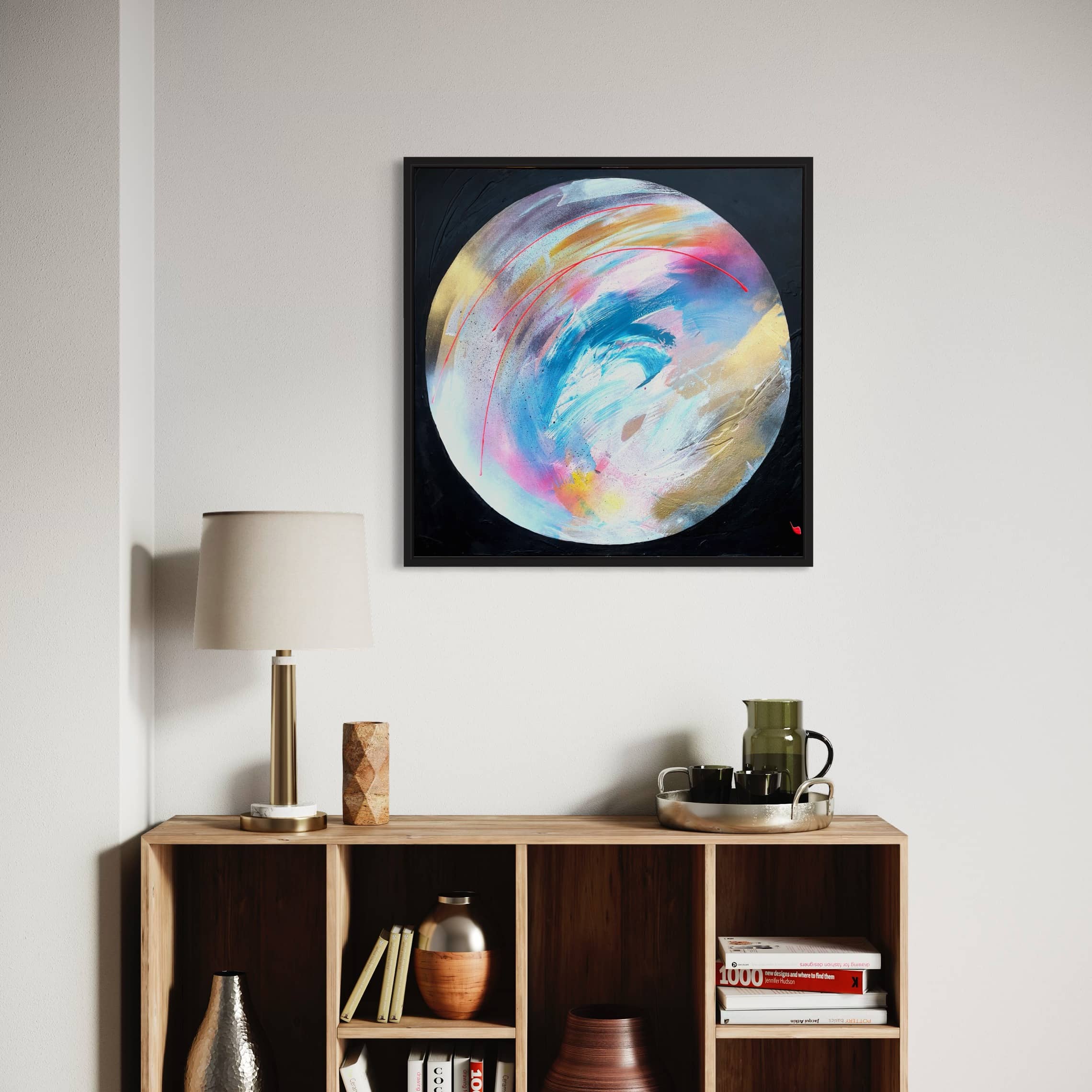 An abstract circular painting by Kate Mayer, titled "Speak Your Truth - Original Painting," adorns the wall above a wooden bookshelf. The vibrant colors of this artwork provide a striking contrast against the lamp and decor items on the shelf.