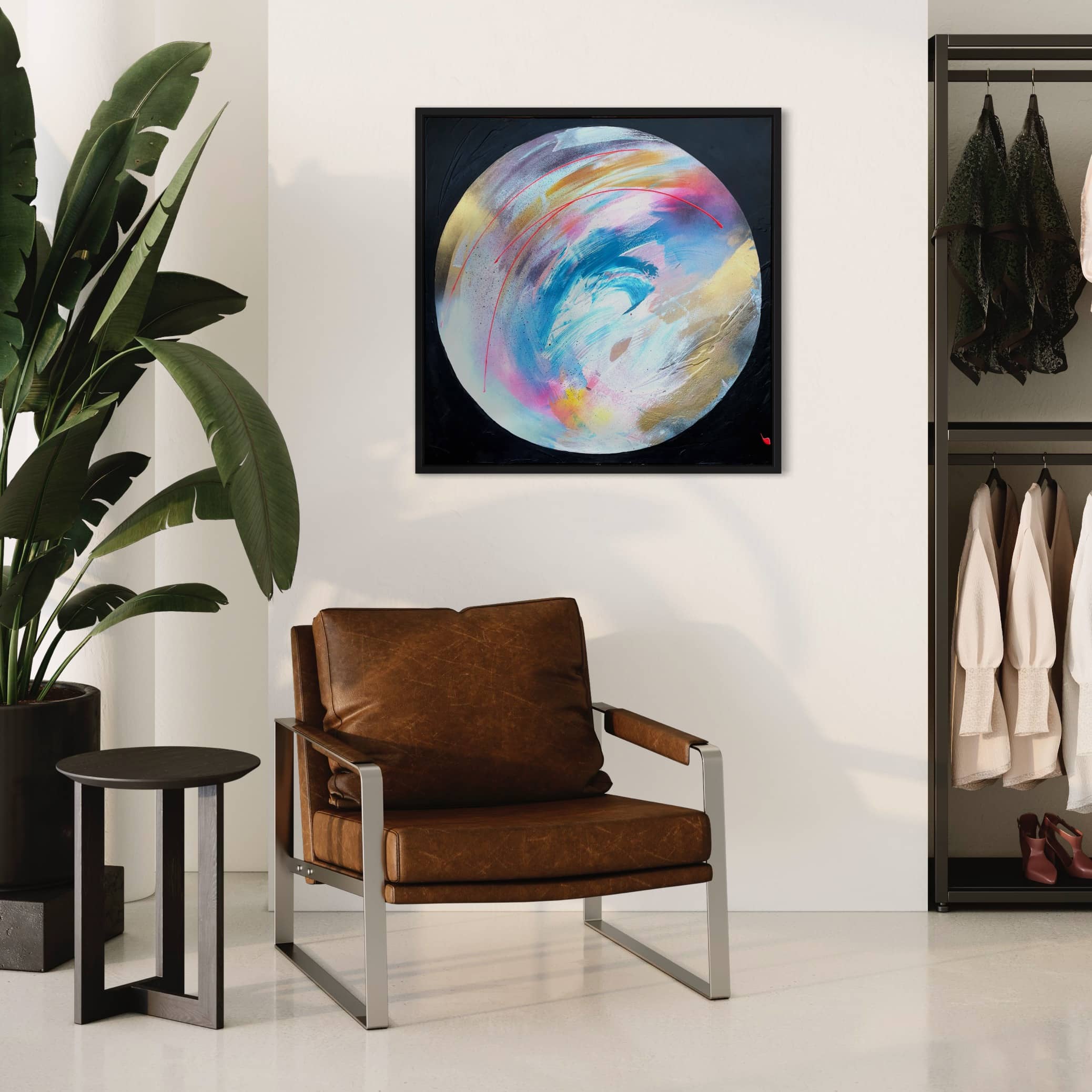 Modern living room with a brown leather chair, black side table, large plant, Kate Mayer’s "Speak Your Truth" original painting, and a clothing rack in the background.