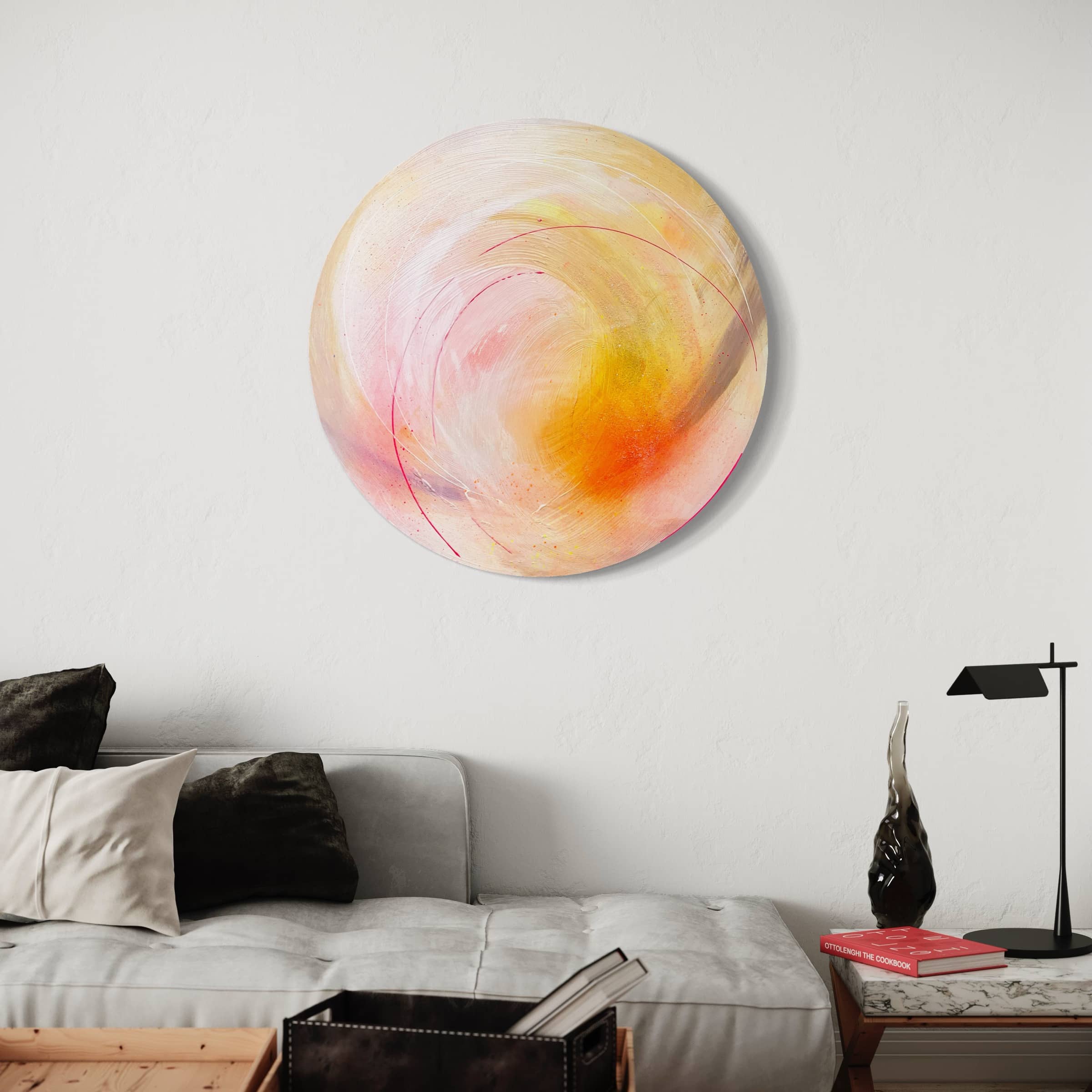 The wall above a minimalist sofa and sleek black lamp is adorned with "Happiness Is A Place Within - Original Painting," a circular abstract artwork by Kate Mayer that features swirls of pink, orange, and yellow enhanced with diamond dust.