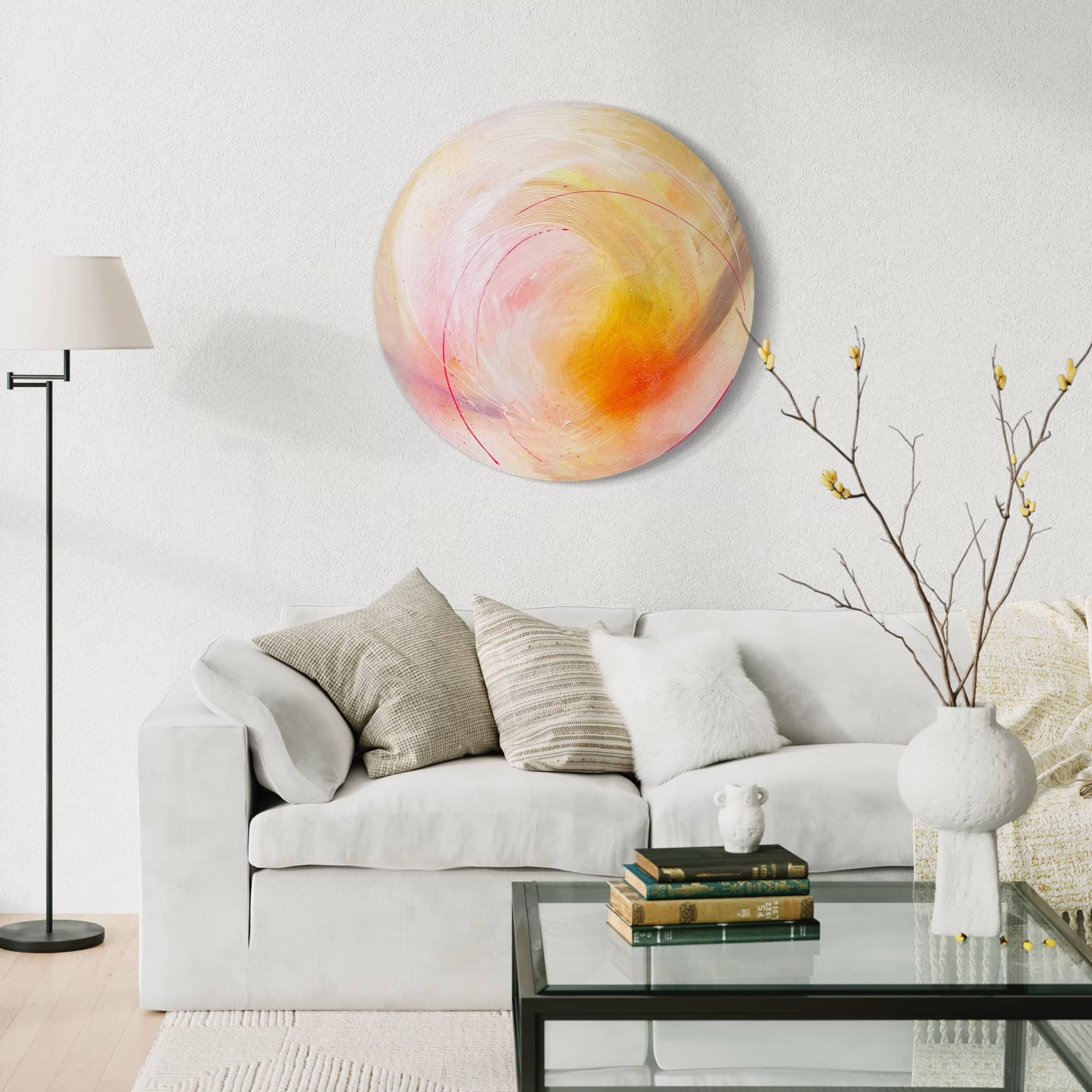 A modern living room showcases a white sofa, cozy pillows, and "Happiness Is A Place Within" by Kate Mayer. A floor lamp casts a warm glow over the glass coffee table and vase with branches, while diamond dust subtly shimmers in the decor.