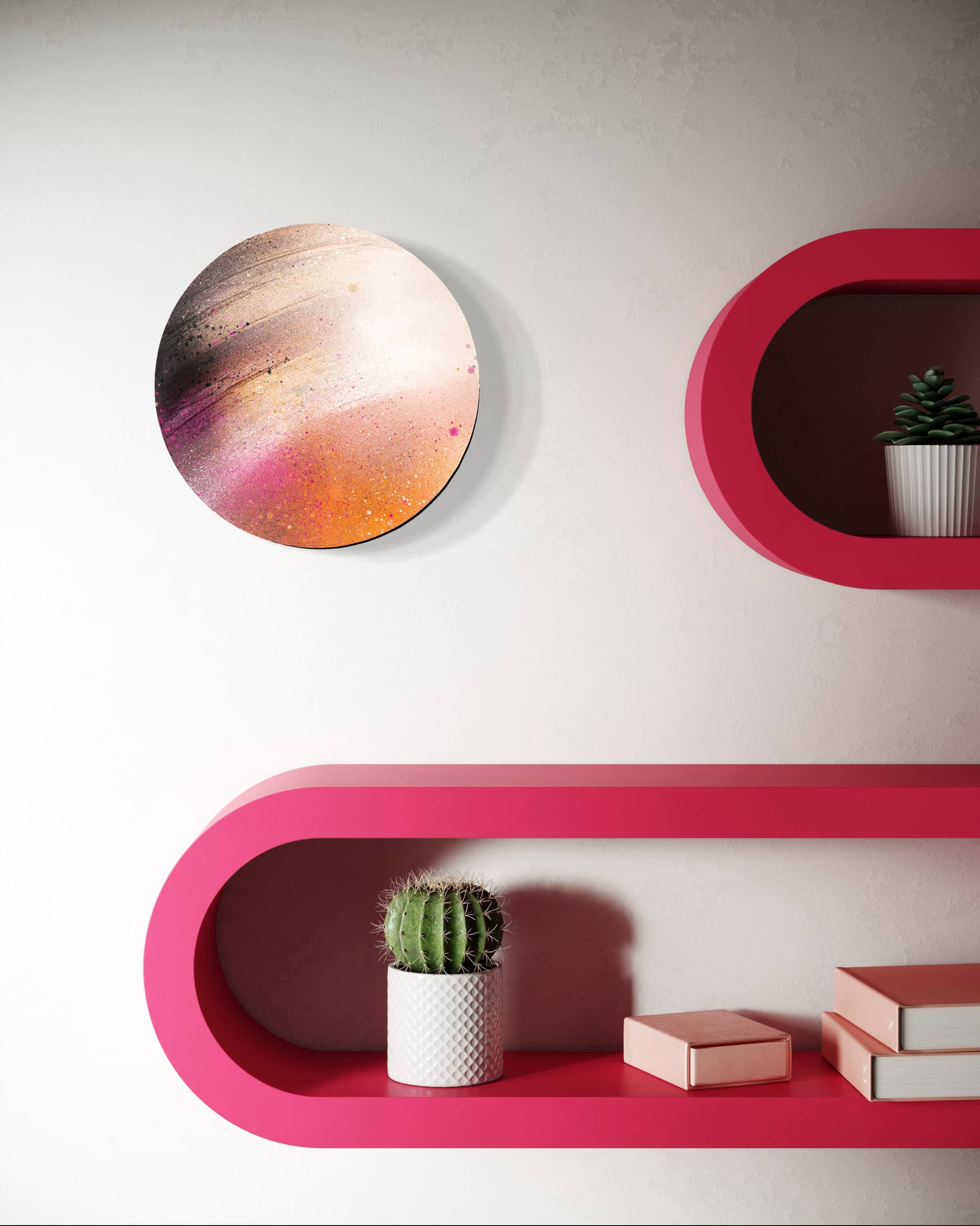 “Heaven” by Kate Mayer, a circular plywood art piece, hangs above pink shelves with a cactus, plants, and books.
