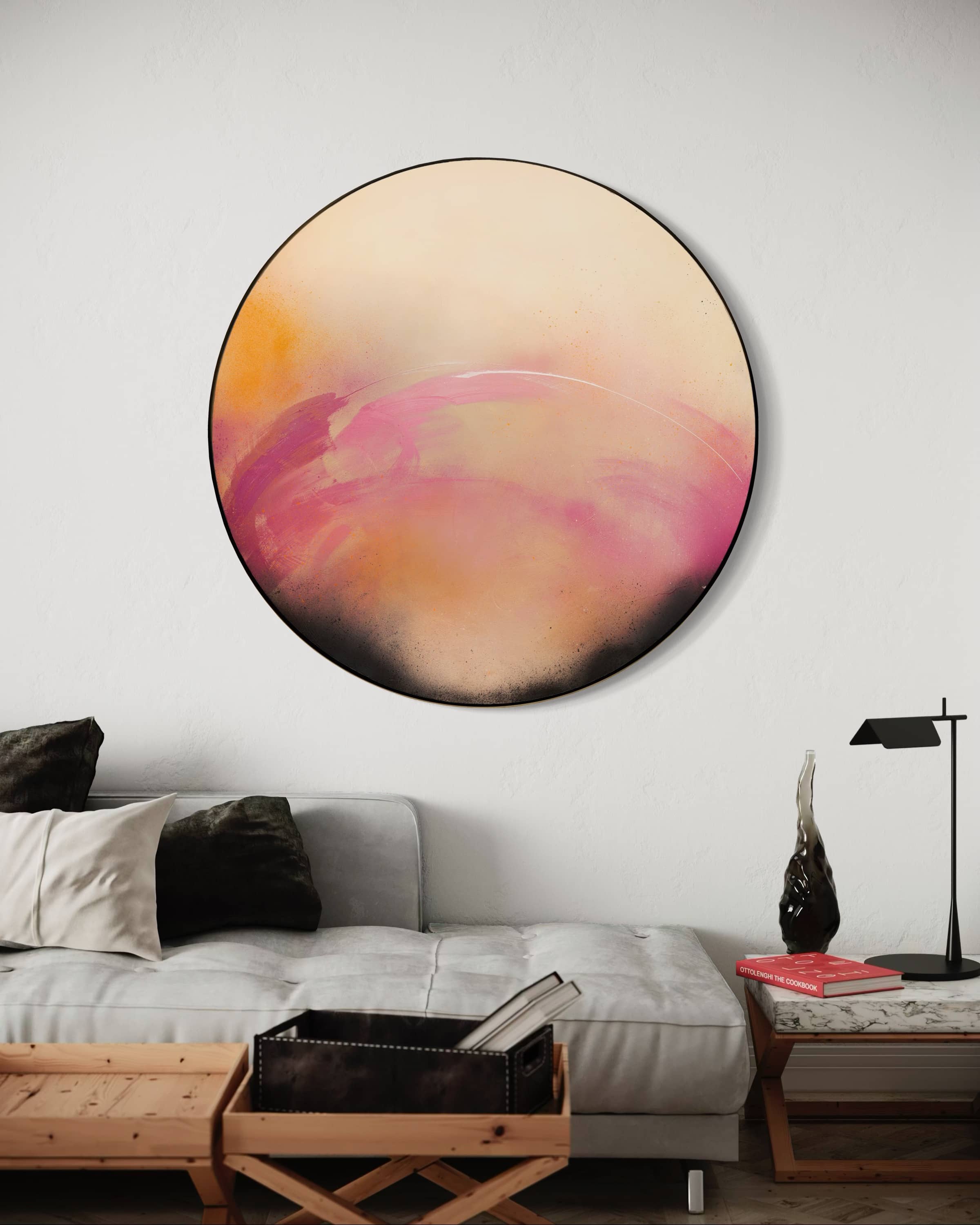 “I Wait With Good Intentions” by Kate Mayer, an abstract round painting in pink, orange & beige, hangs above a modern sofa.